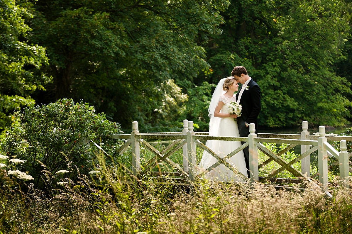 Bride and groom on white painted bridge at Exton Park, Rutland