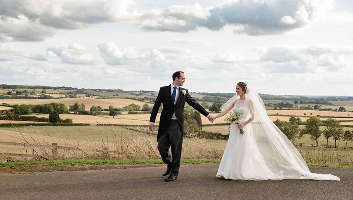 Bride & Groom walking with a view of Northamptonshire countryside in the background