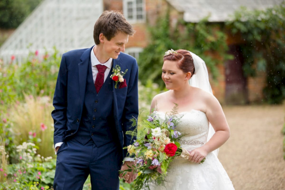Bride and groom walking in the rain at Kelmarsh Hall