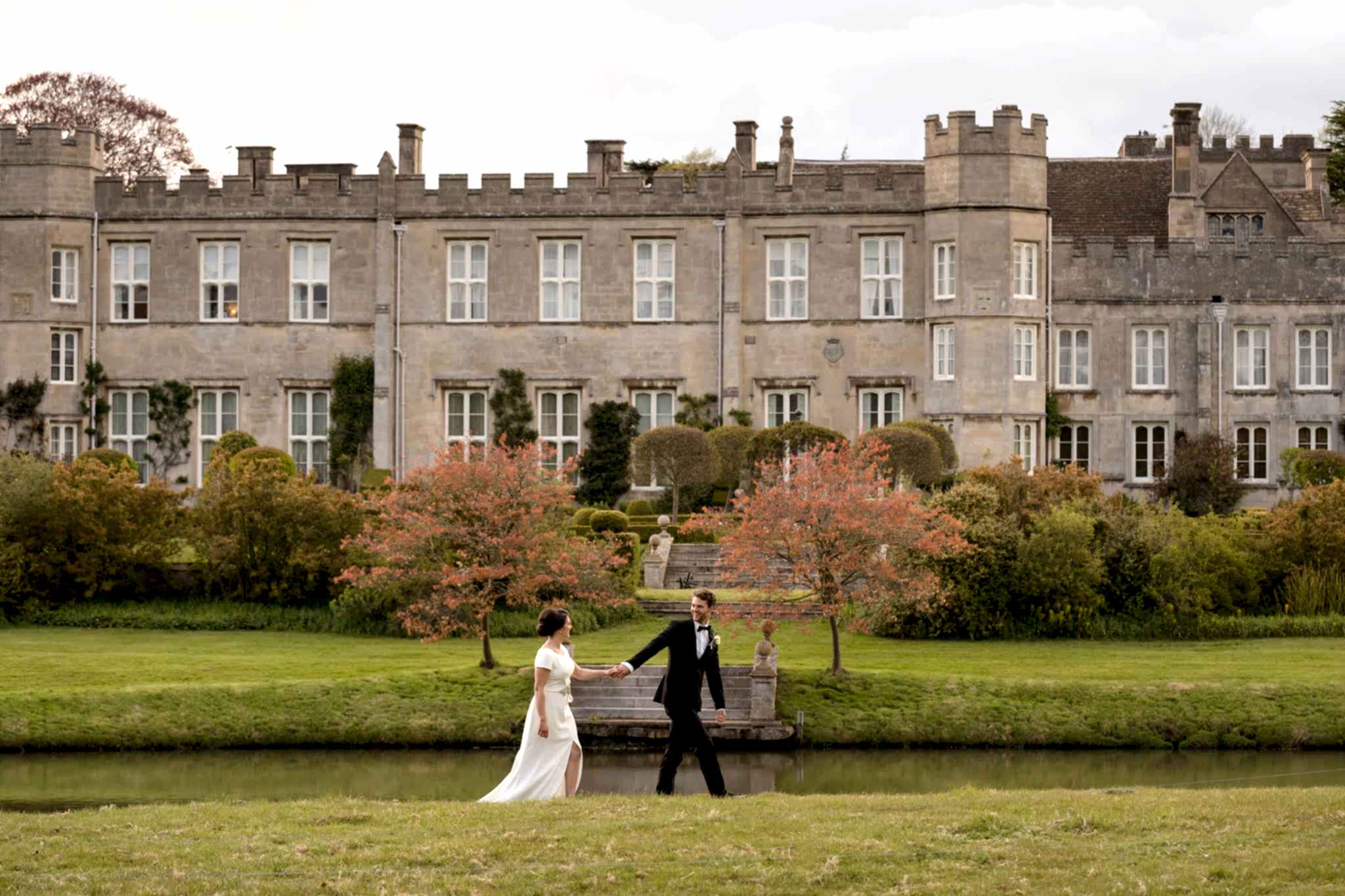 Bride and groom walking in front of Deene Park house