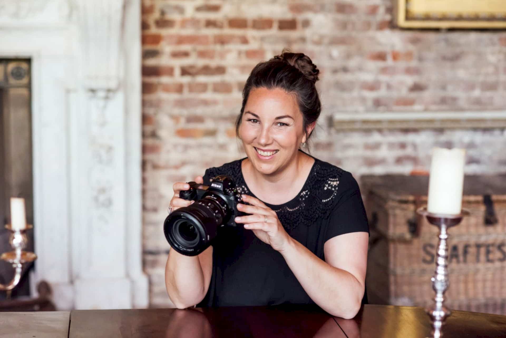 Sarah Vivienne sitting at a table holding a camera