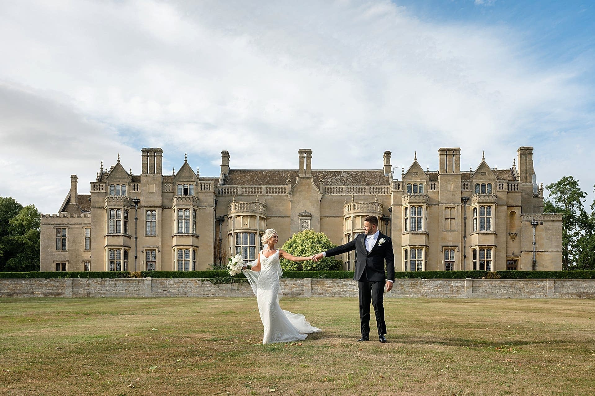 Bride and groom walking in front of a country house