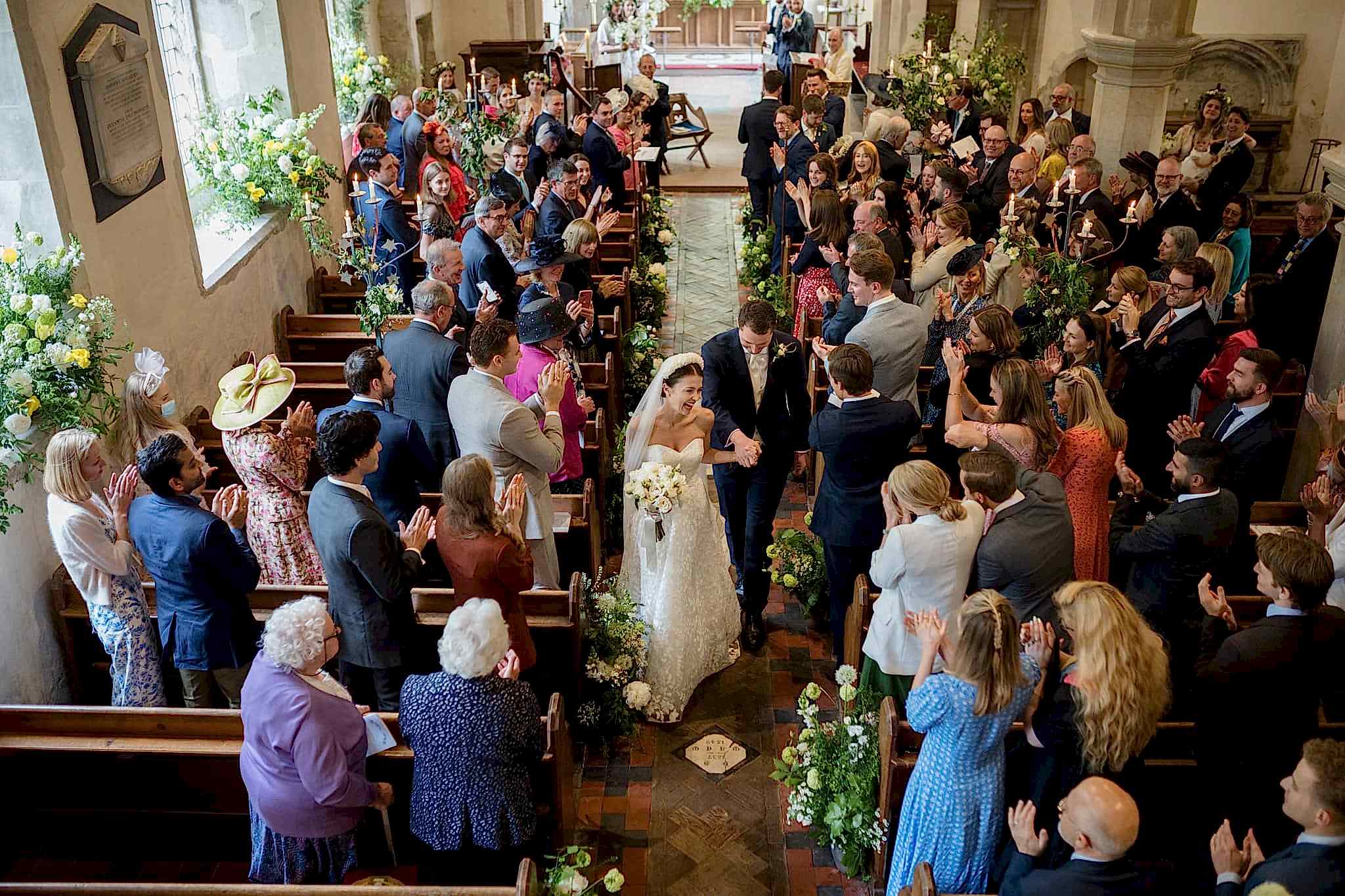 A view of the bride and groom walking down the aisle from the organist's balcony at Grantchester church