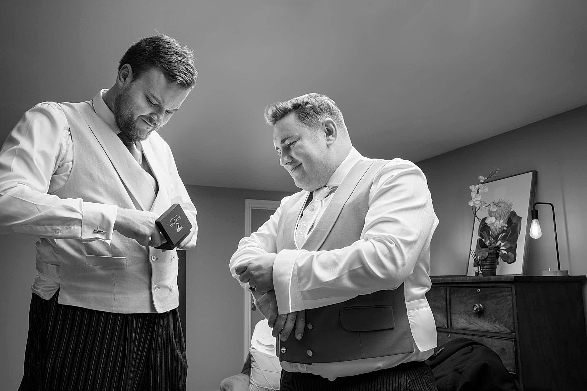 The best man passing the groom his cufflinks to put on