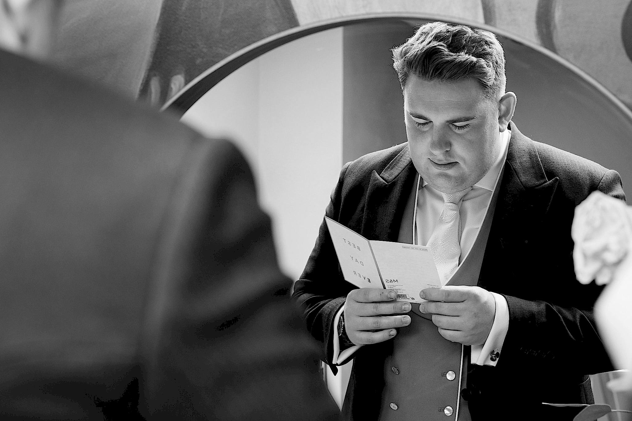 A mirror reflection of the groom reading a wedding day card from the bride