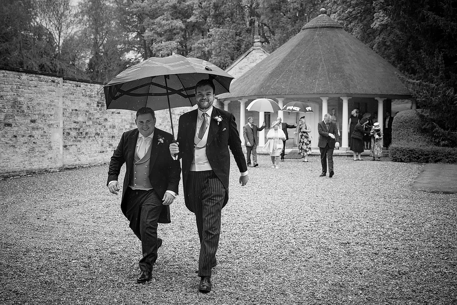The groom and best man arriving at Exton Park chapel in the rain