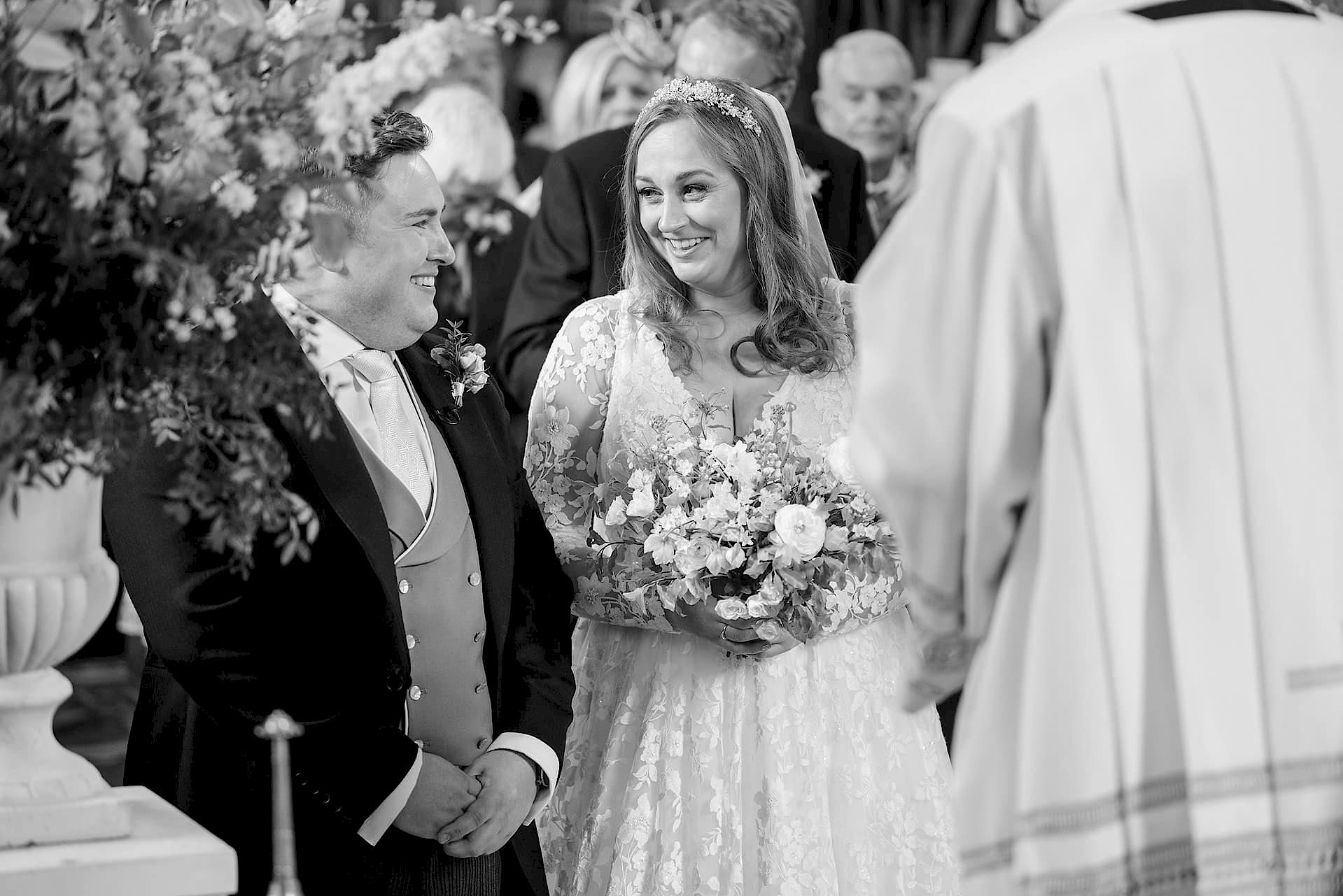 Bride and groom exchanging smiles as they meet at the altar for their marriage ceremony