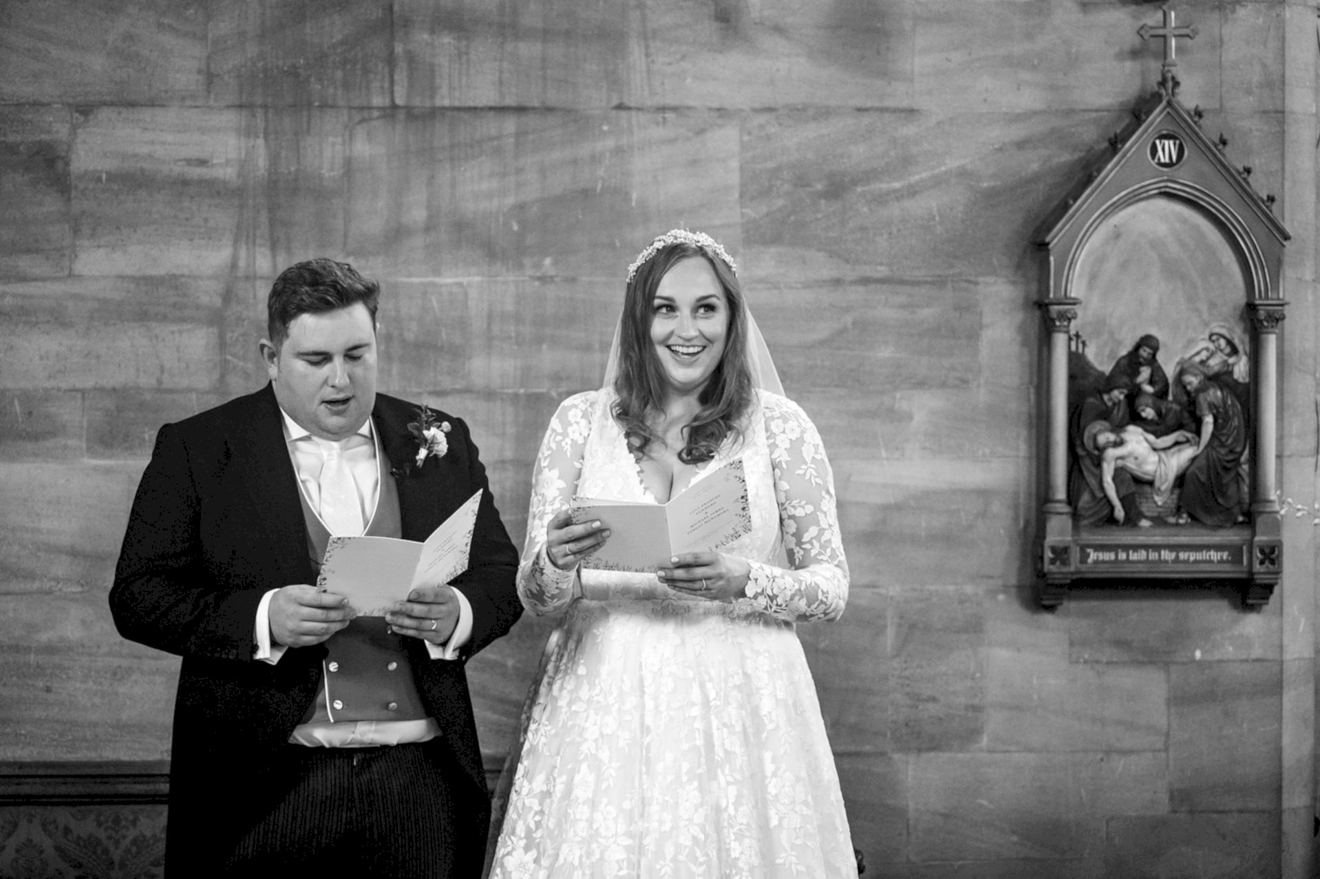 Bride smiling at a wedding guest during a hymn in their marriage ceremony at Exton Park chapel