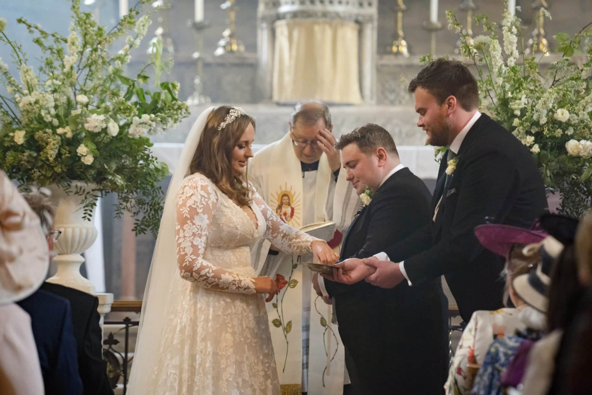 The bride taking the groom's ring from the best man during their wedding at Exton Park chapel