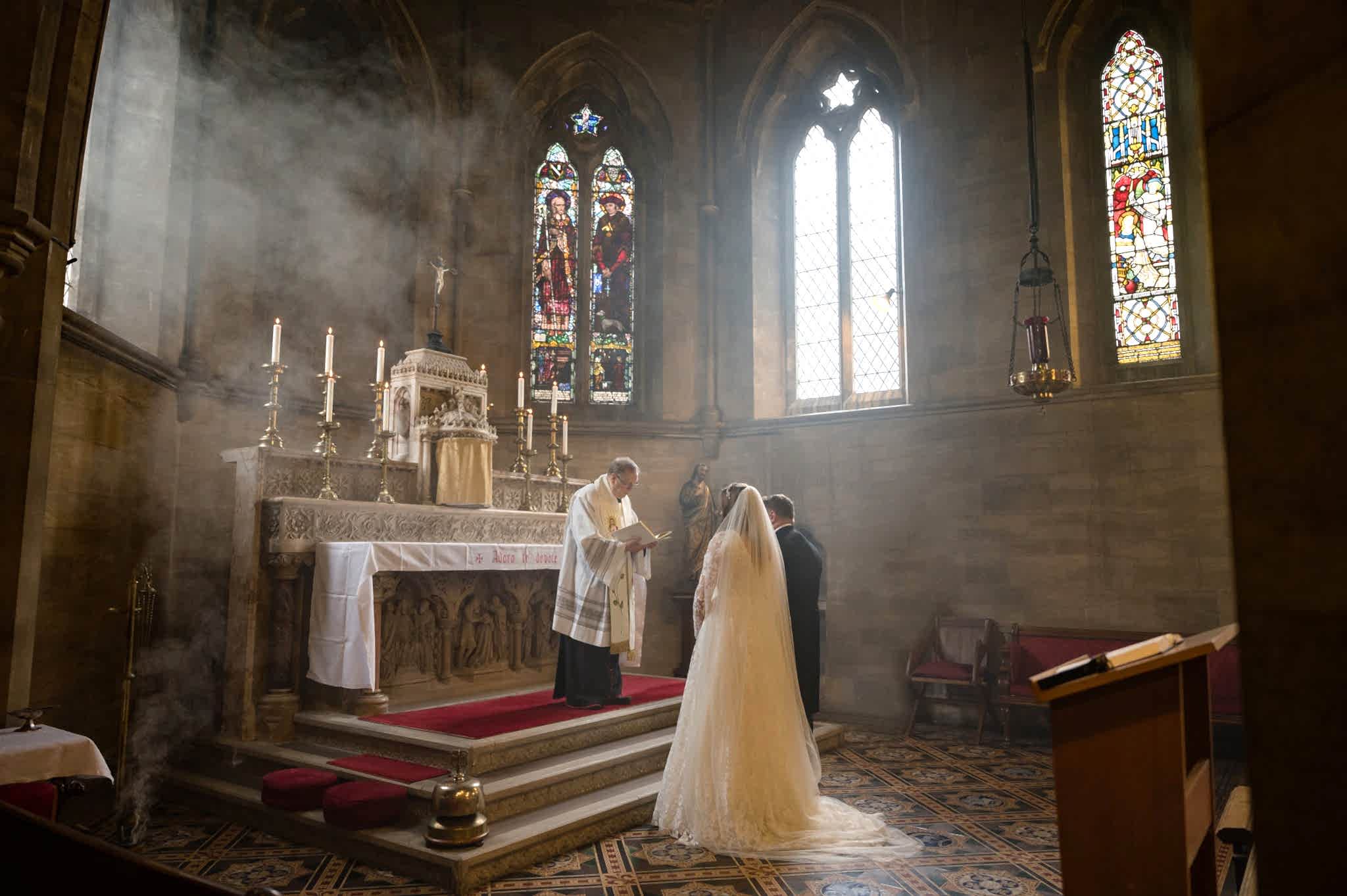 Bride and groom standing at the altar for prayers at the end of their marriage ceremony at Exton Park chapel