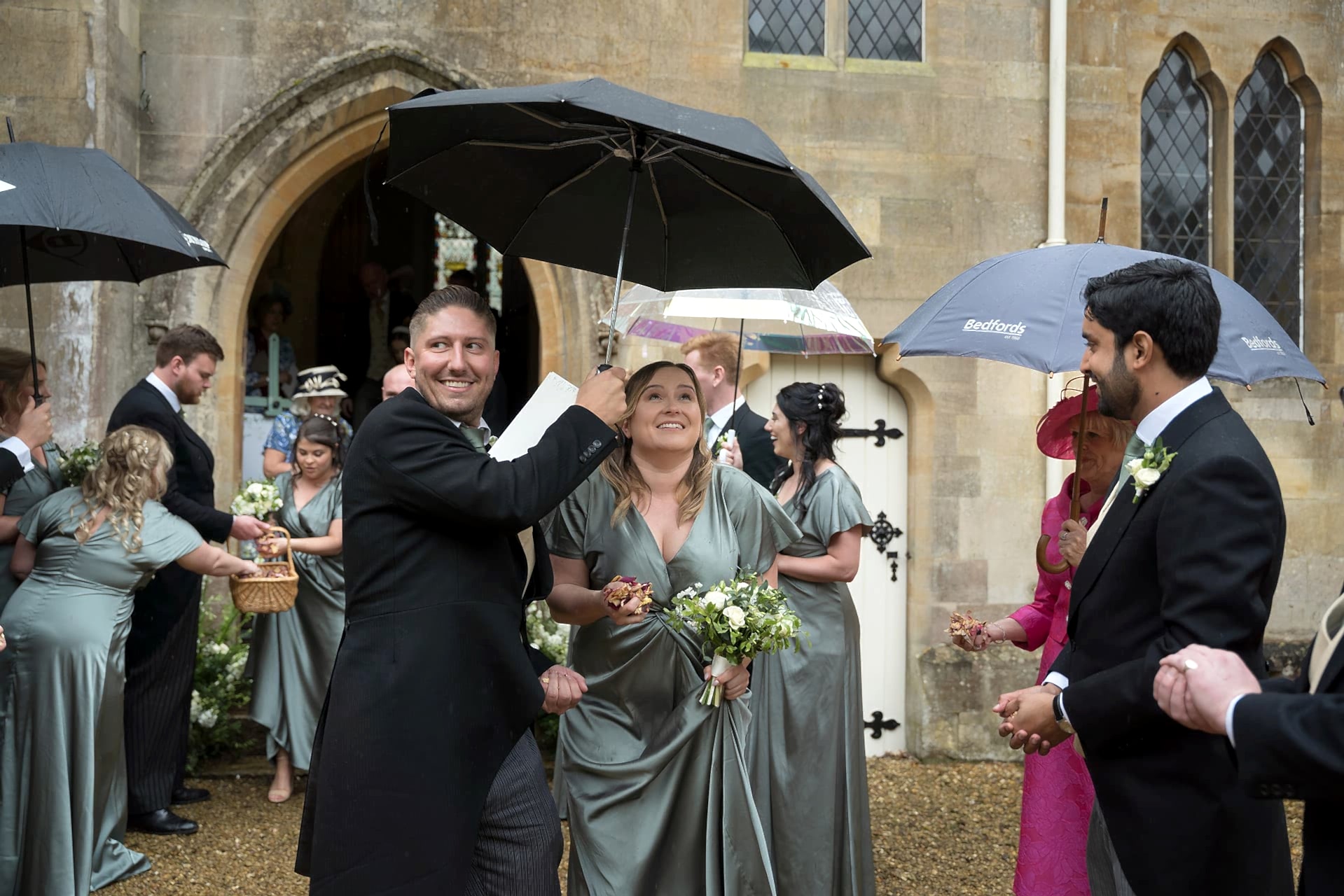 Wedding guests coming out of Exton Park chapel in the rain