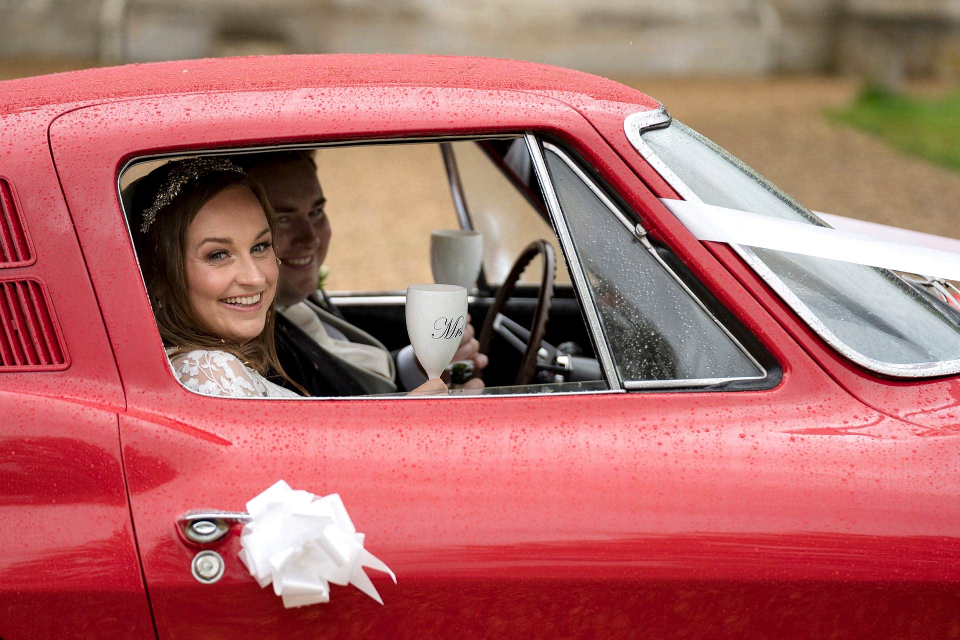 Bride and groom waiting in their wedding car for the rain pass