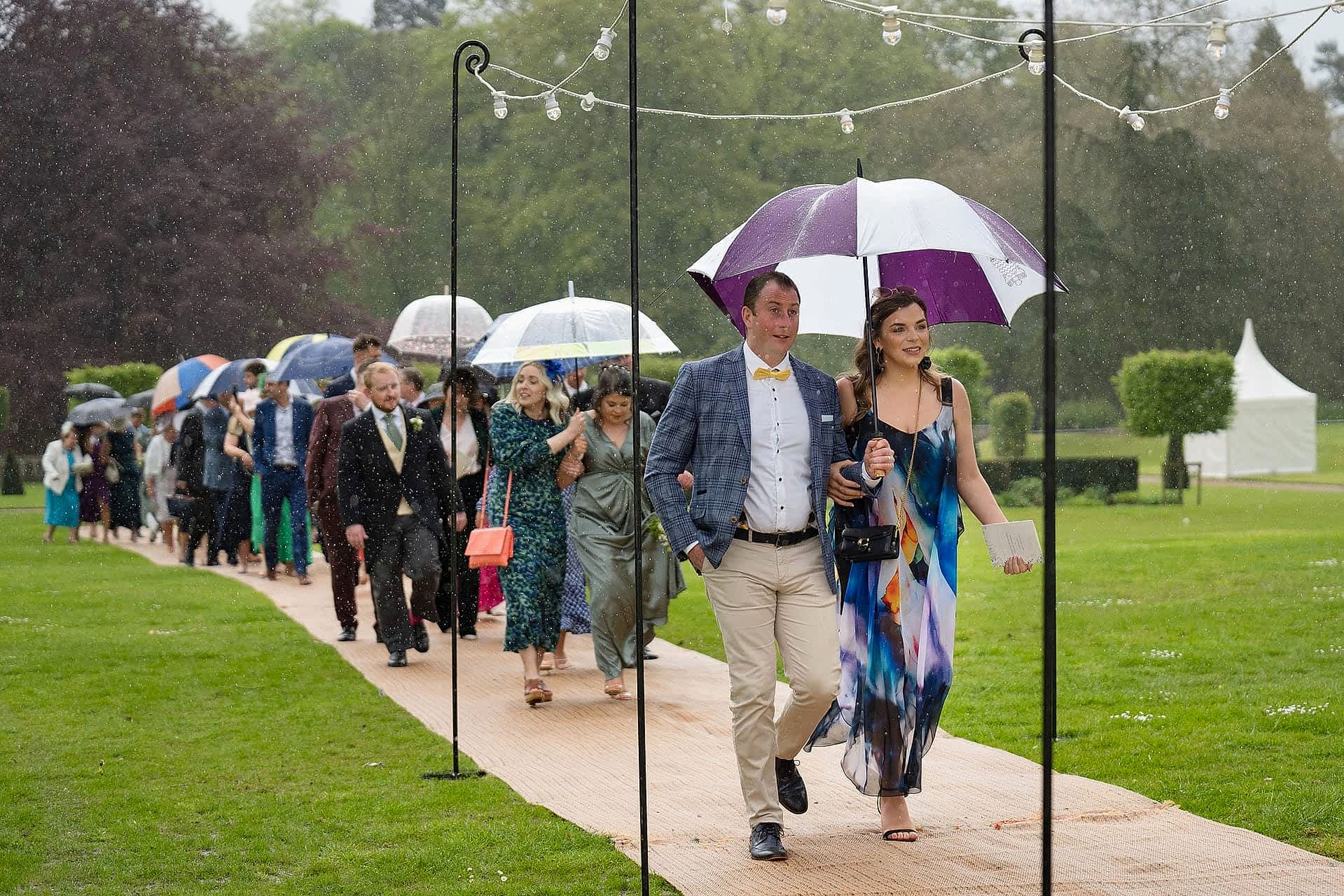 Wedding guests walking into the marquee in the rain at Exton Park