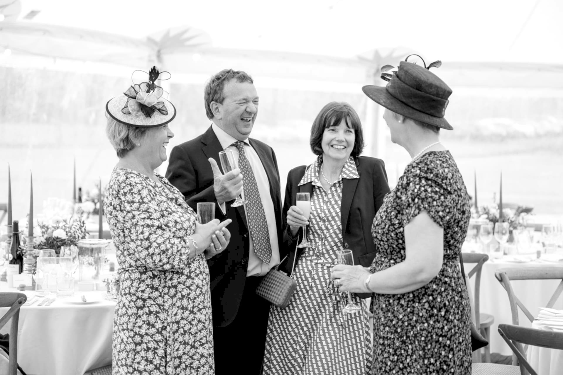 Wedding guests enjoying a rainy drinks reception inside a marquee