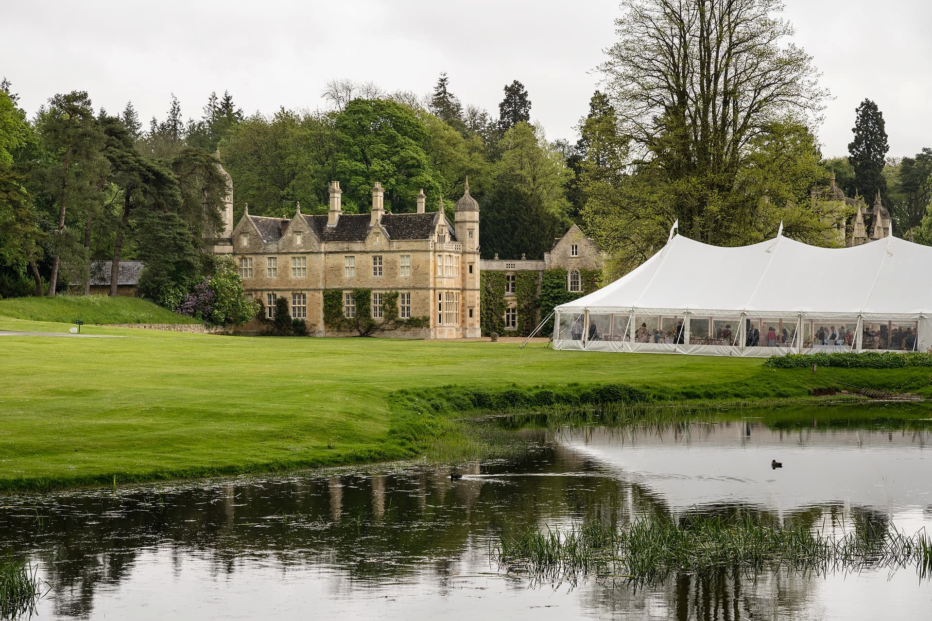 A wedding marquee by the lake in front of Exton Park Hall