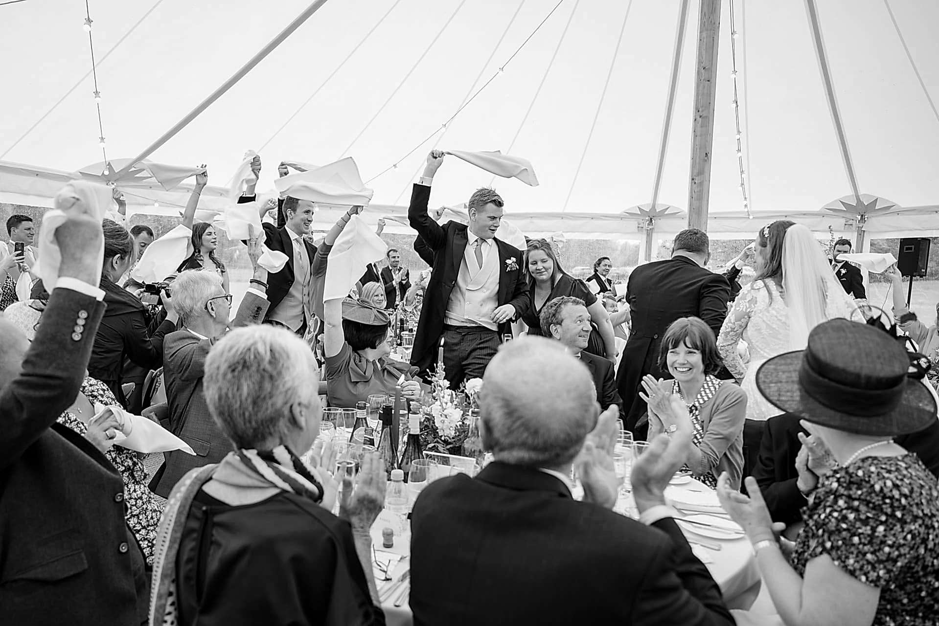 Wedding guests waving their napkins as the bride and groom make their entrance for the wedding breakfast