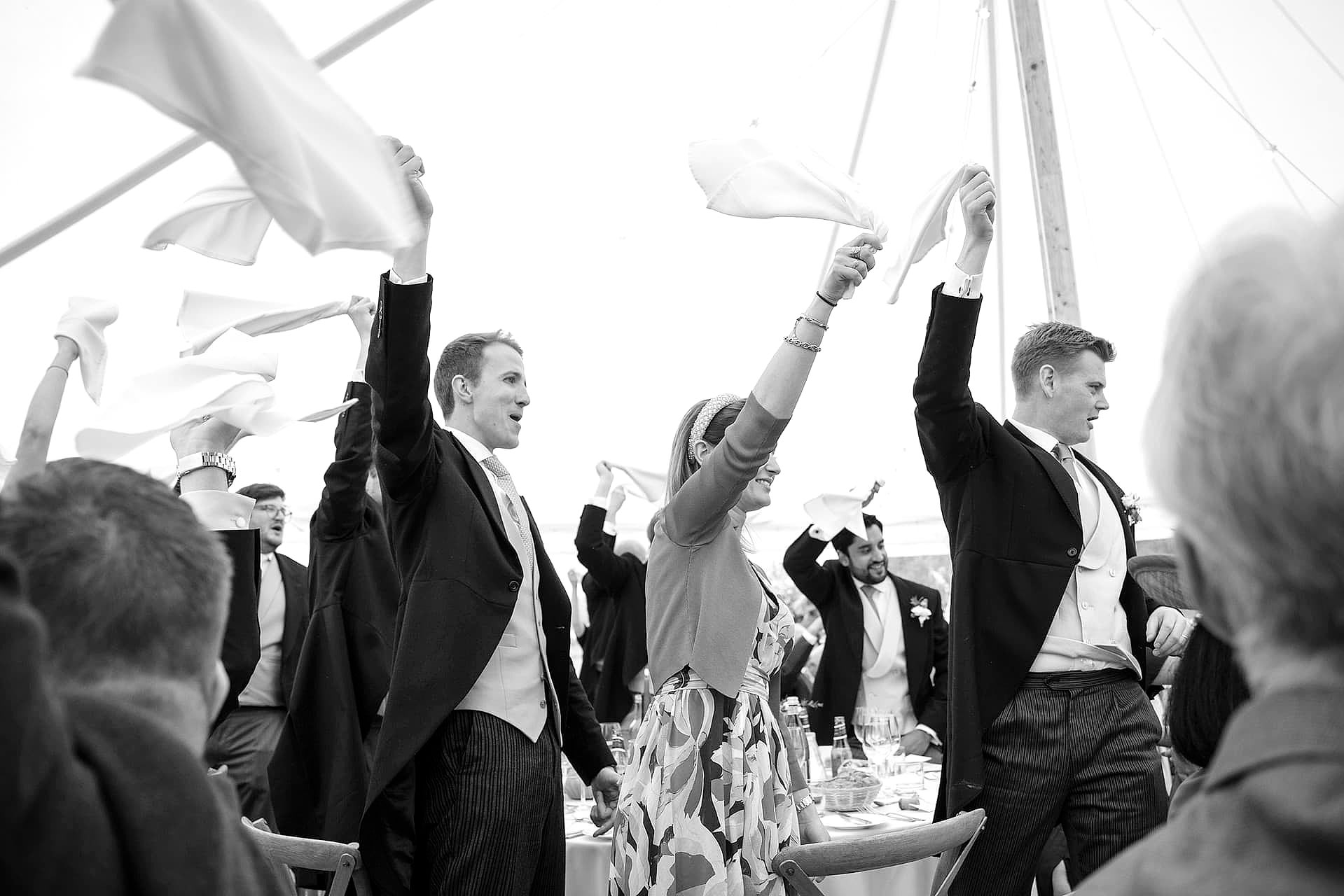 Wedding guests waving their napkins as the bride and groom make their entrance for the wedding breakfast
