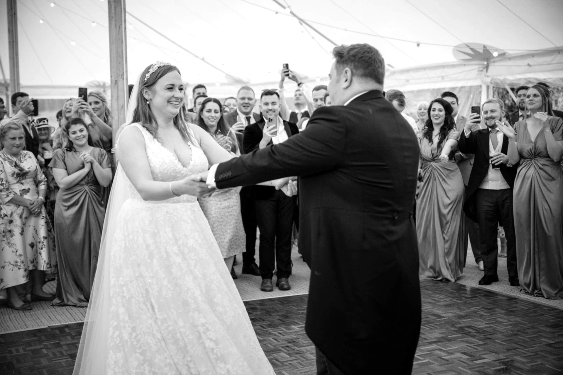 Bride and groom doing their first dance as their guests look on in the background
