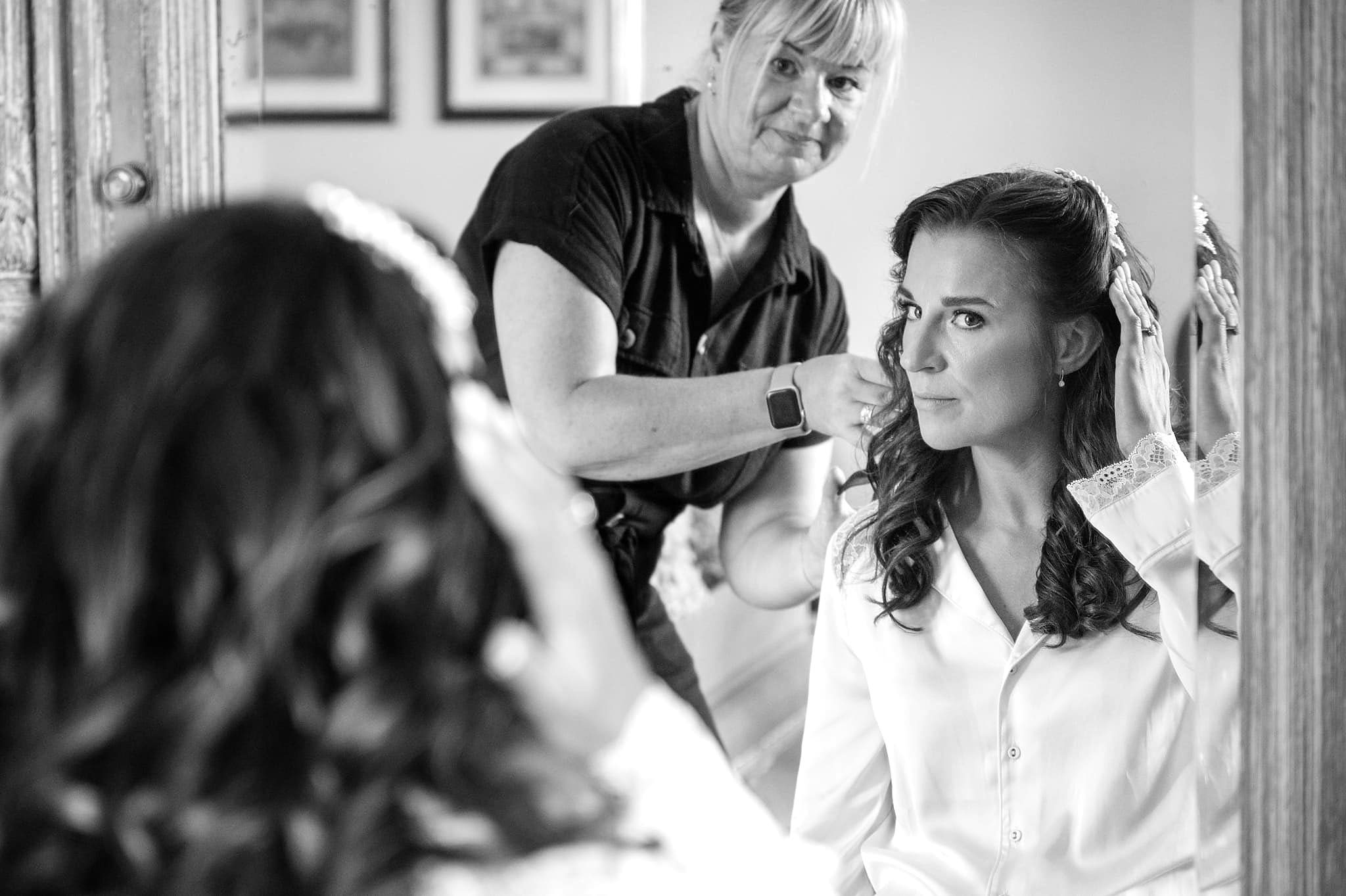 A mirror reflection of the bride having her hair done