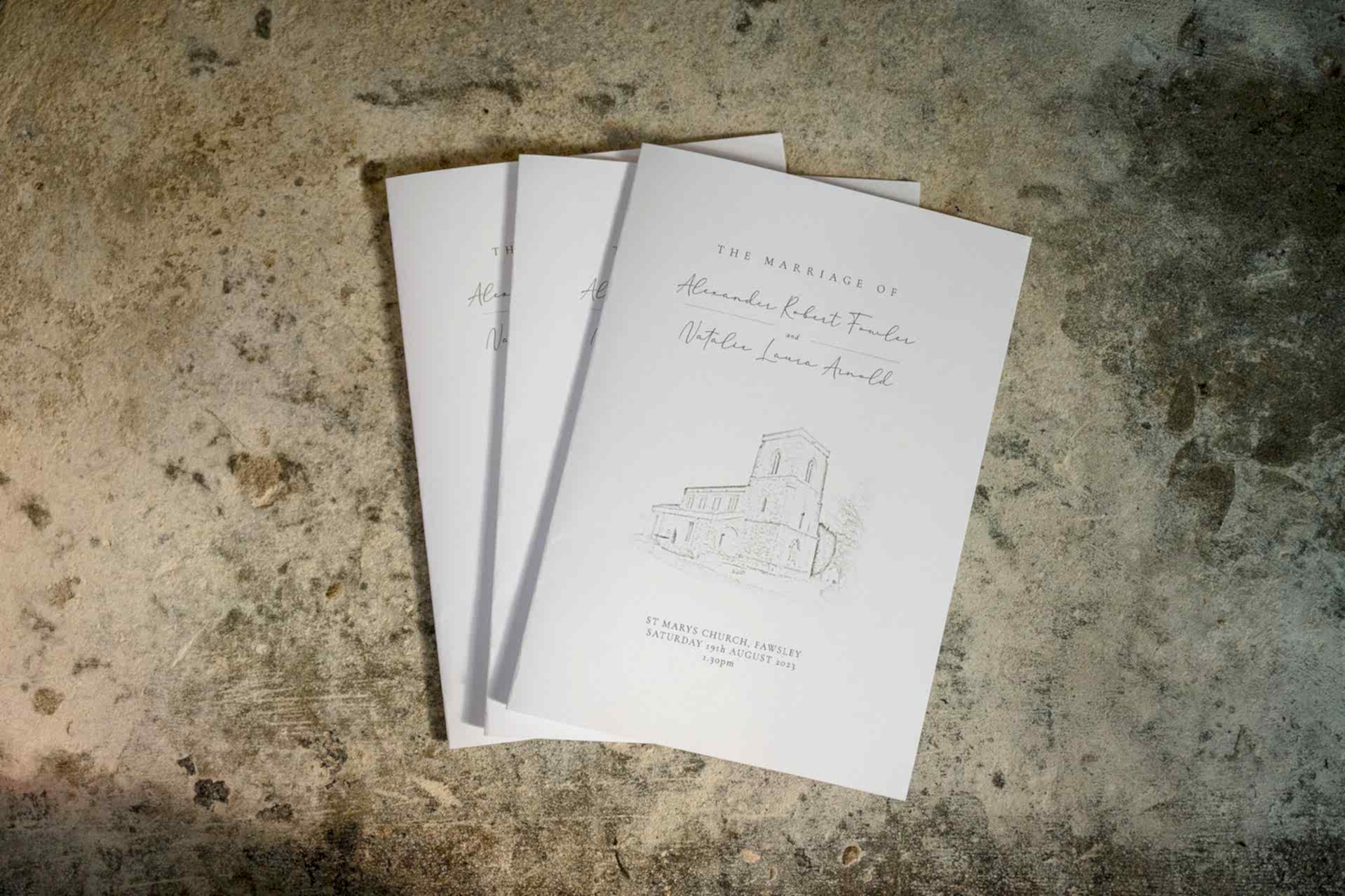 A fan of three order of service booklets for a wedding at Fawsley church
