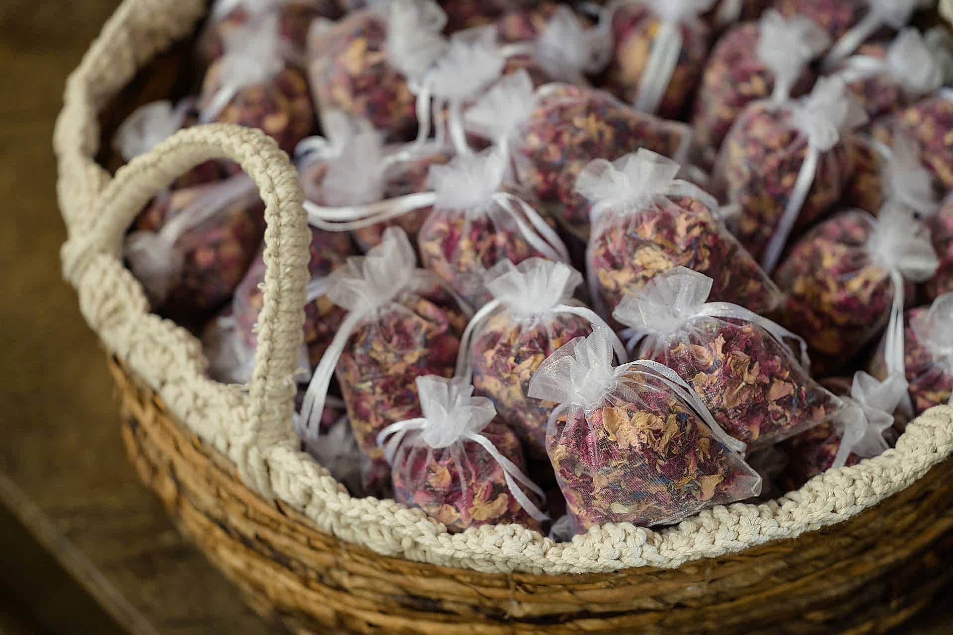 A wicker basket filled with little bags of dried flower petal confetti
