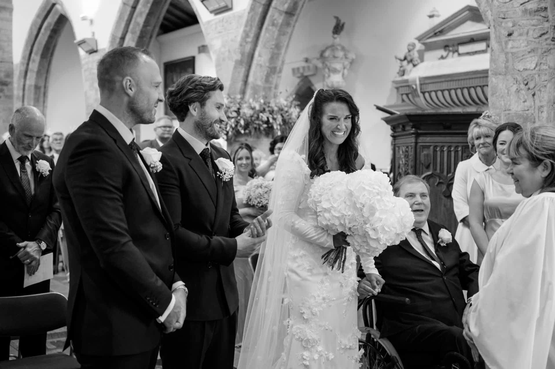 The bride reaches the groom at the altar at Fawsley church