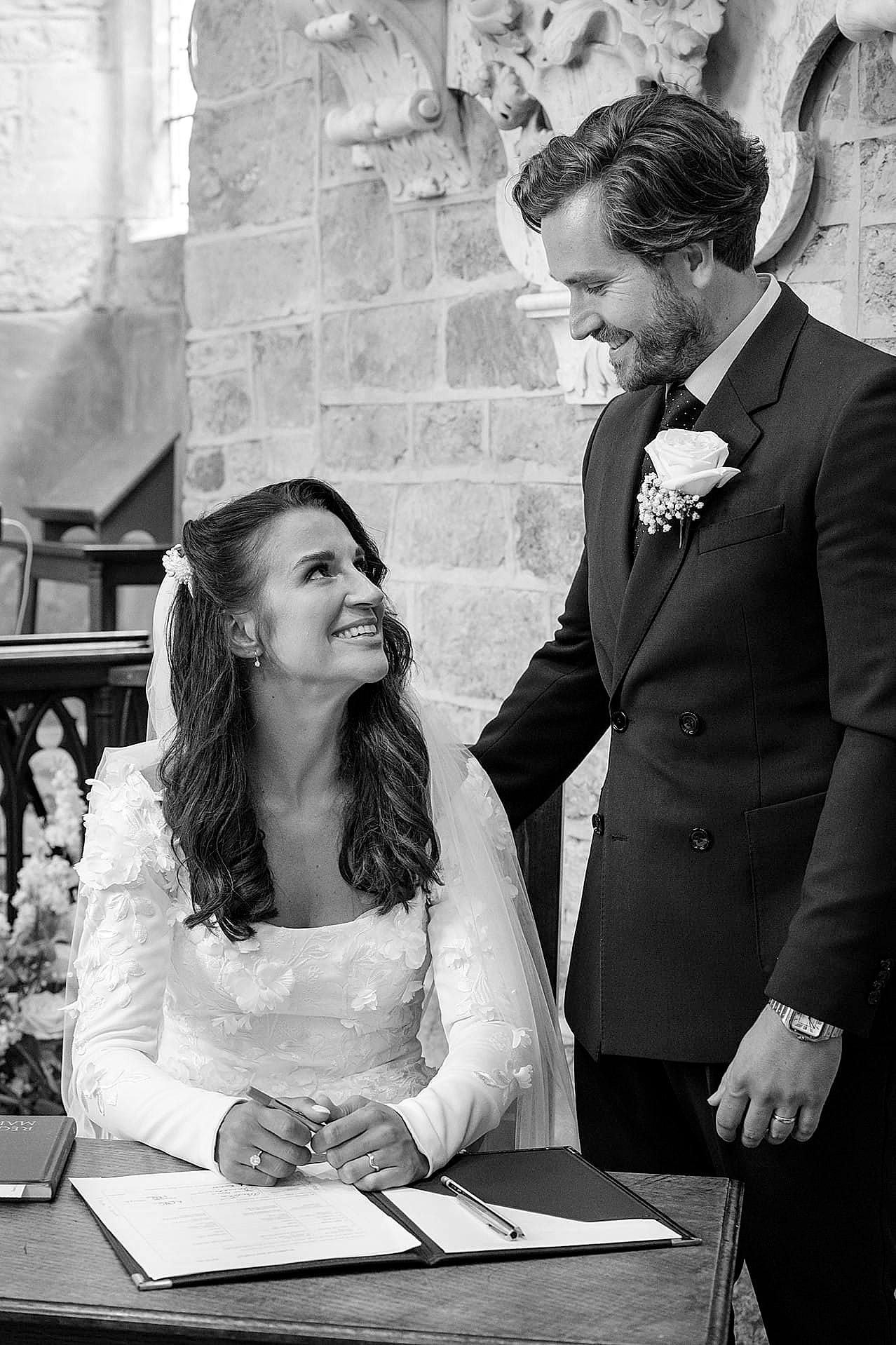 The bride and groom looking at each other after they've signed the marriage register at Fawsley church