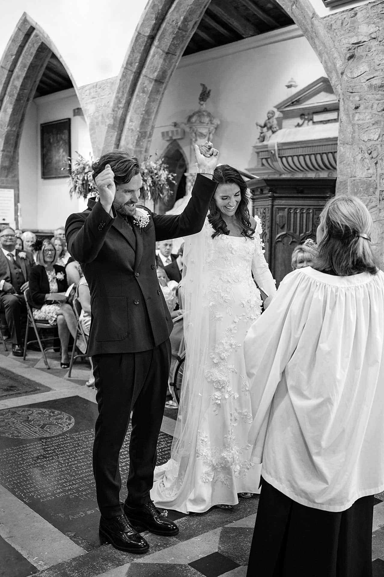 The bride and groom cheering as they're pronounced husband and wife at Fawsley church