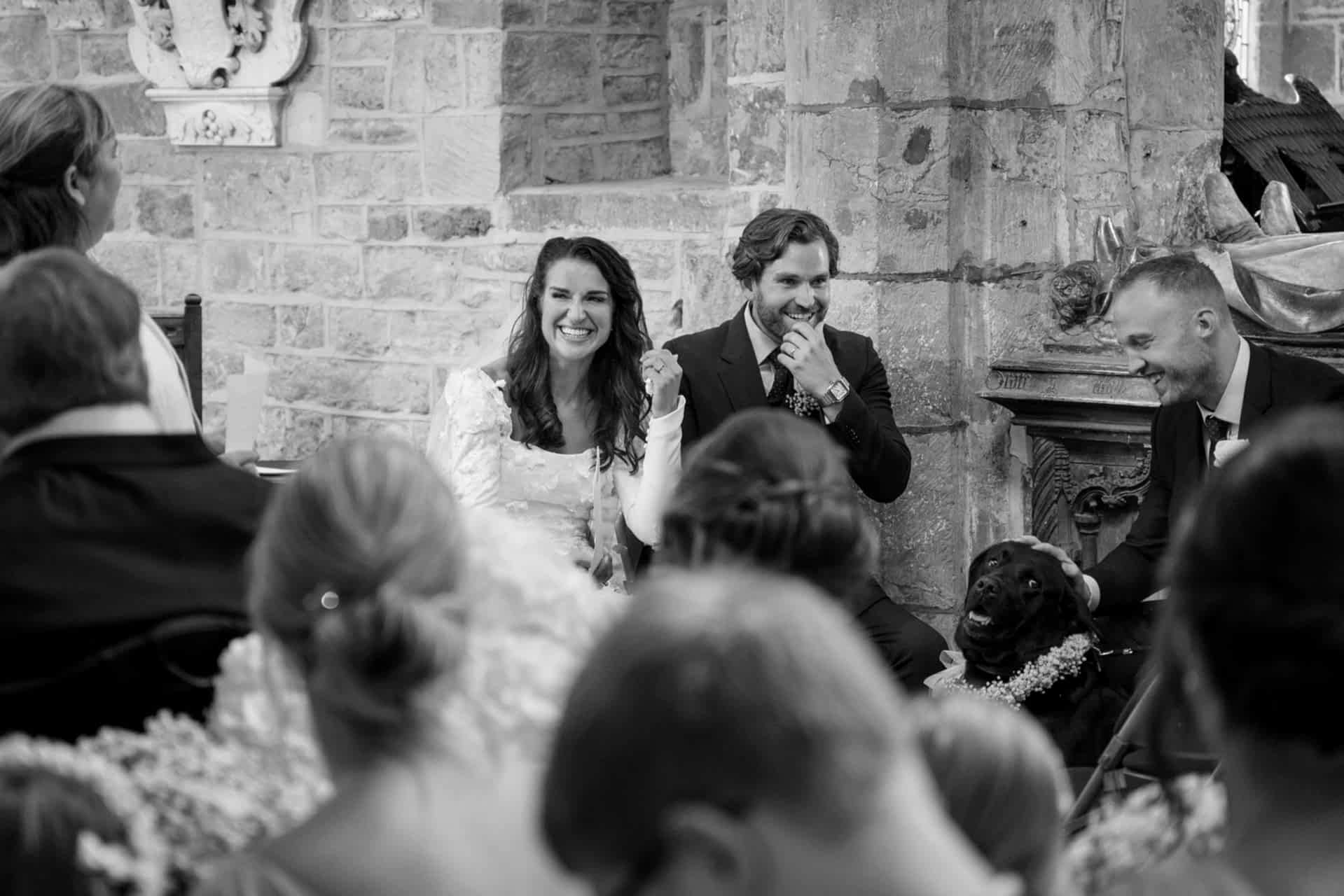 The bride, groom and even their dog with shocked expressions on their faces as the vicar makes a joke during their address