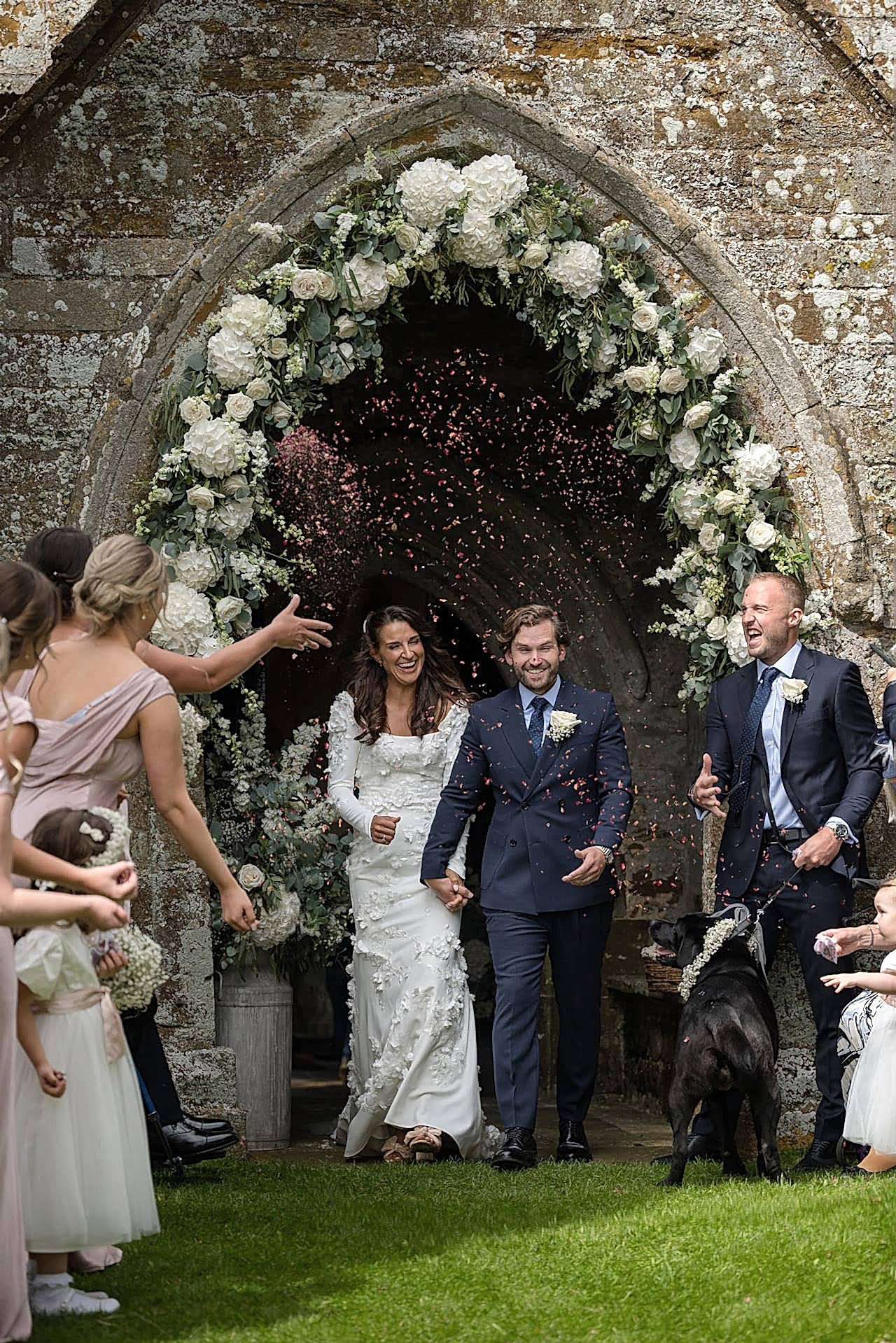 Bride and groom coming out of Fawsley church to their guests ready to throw confetti