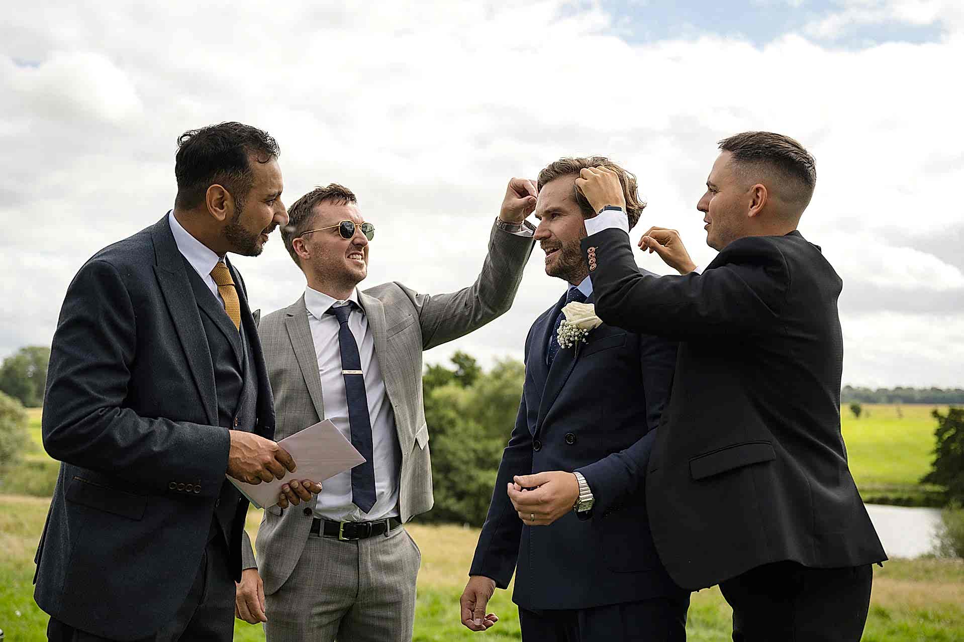 Three of the groom's friends removing confetti from his hair
