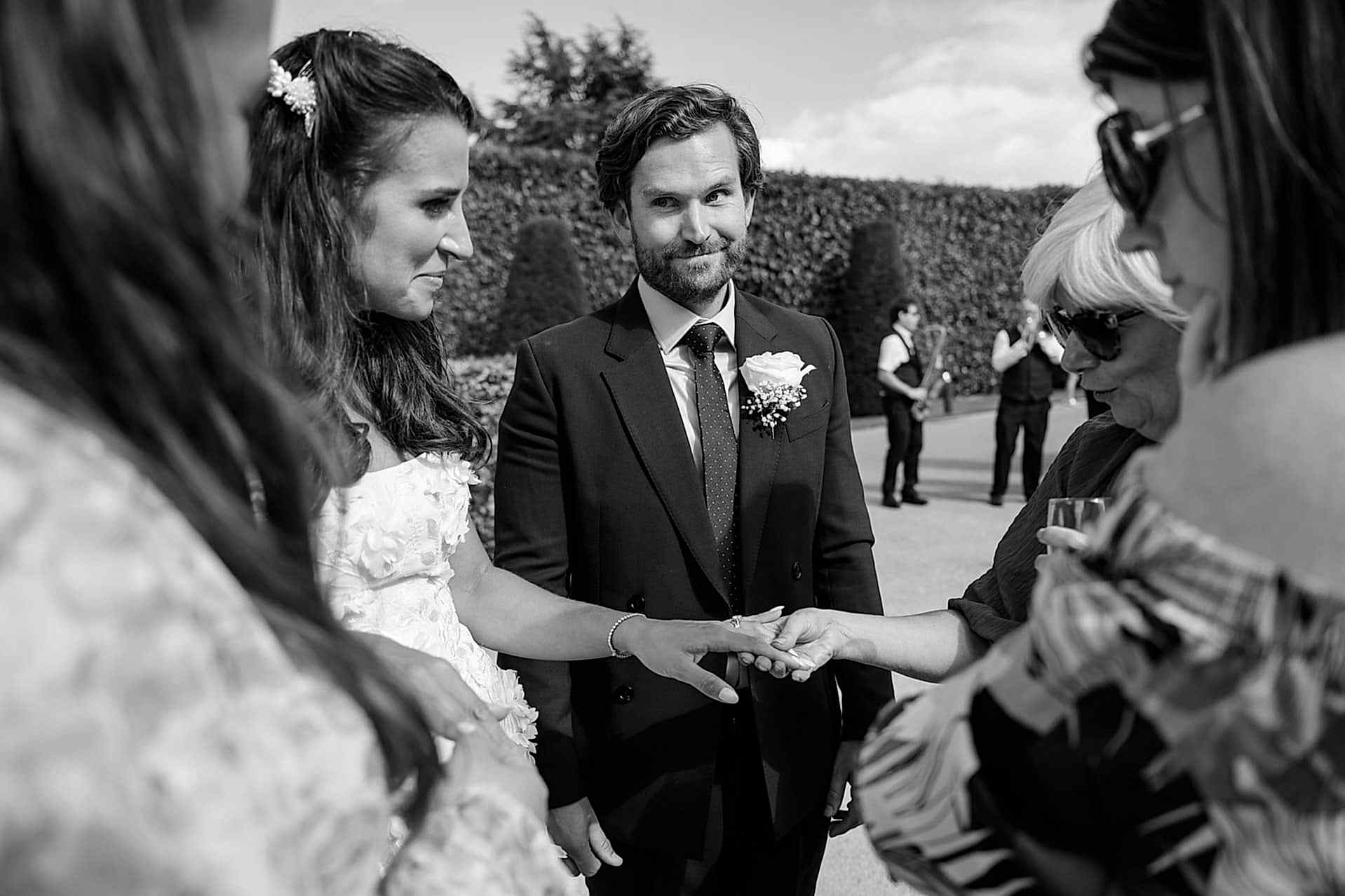 A wedding guest checking out the bride's wedding ring as the groom looks on