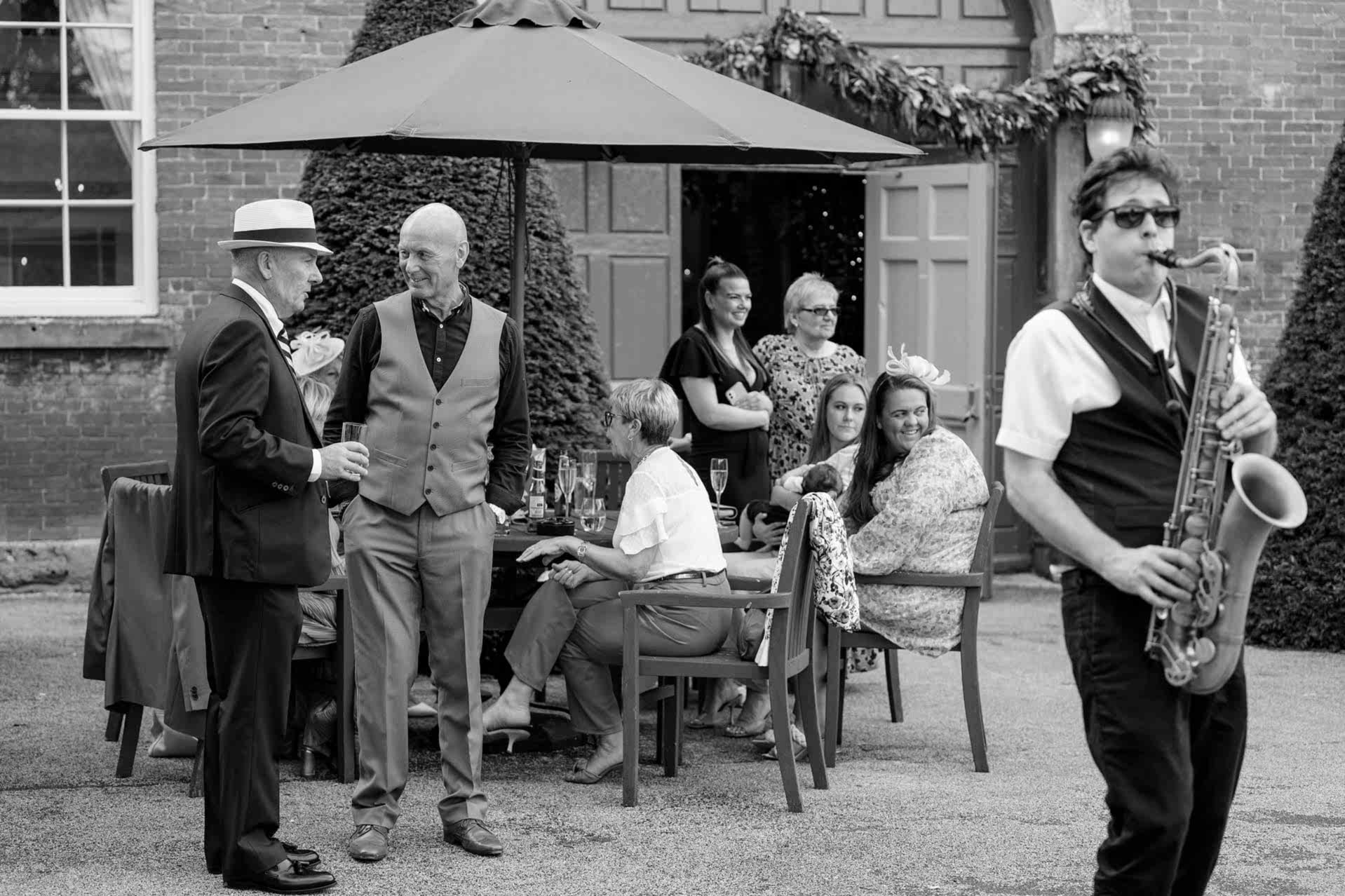 Wedding guests enjoying a wedding drinks reception outside Knightley Court at Fawsley Hall
