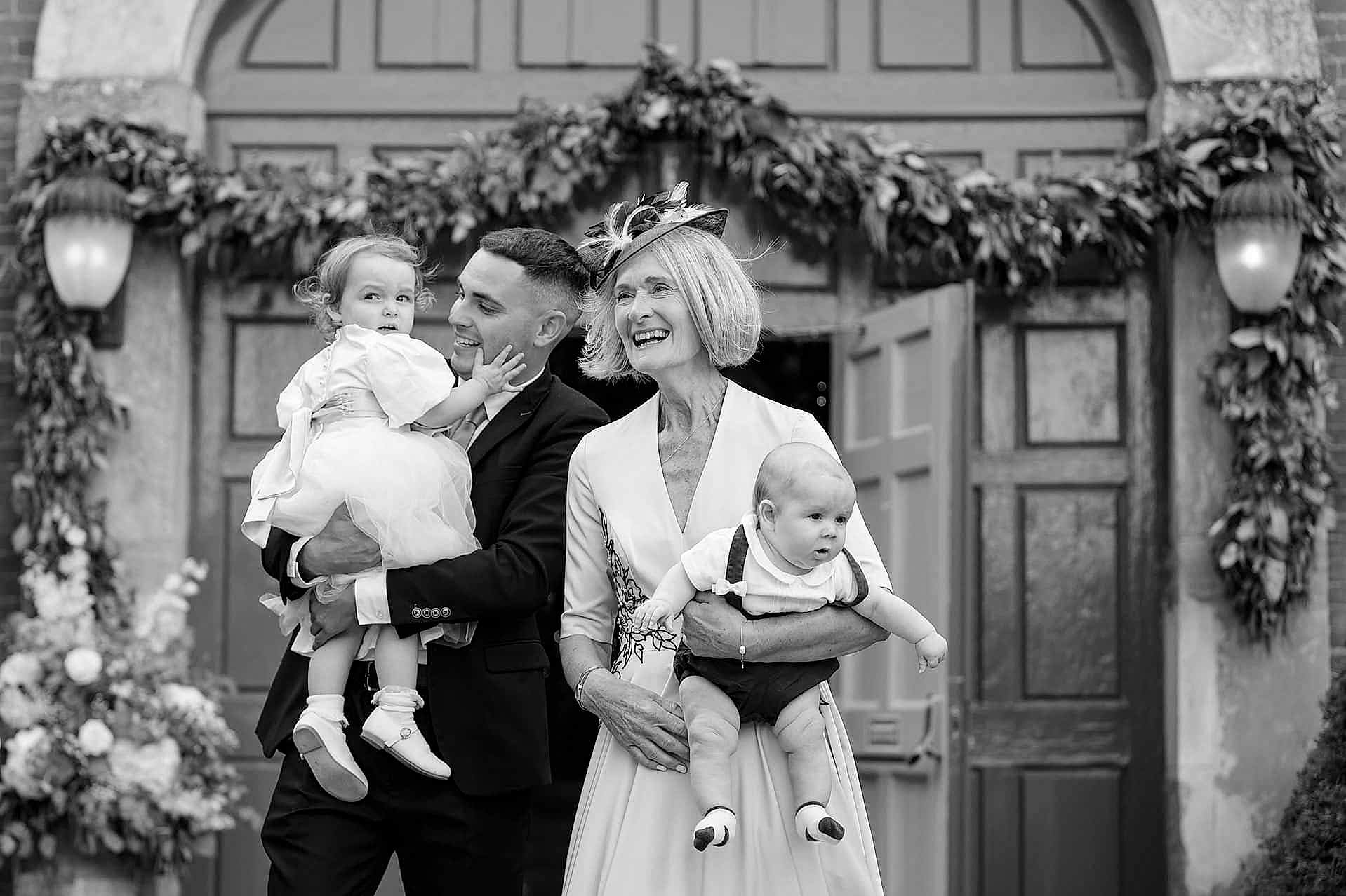Wedding guests enjoying a wedding drinks reception outside Knightley Court at Fawsley Hall