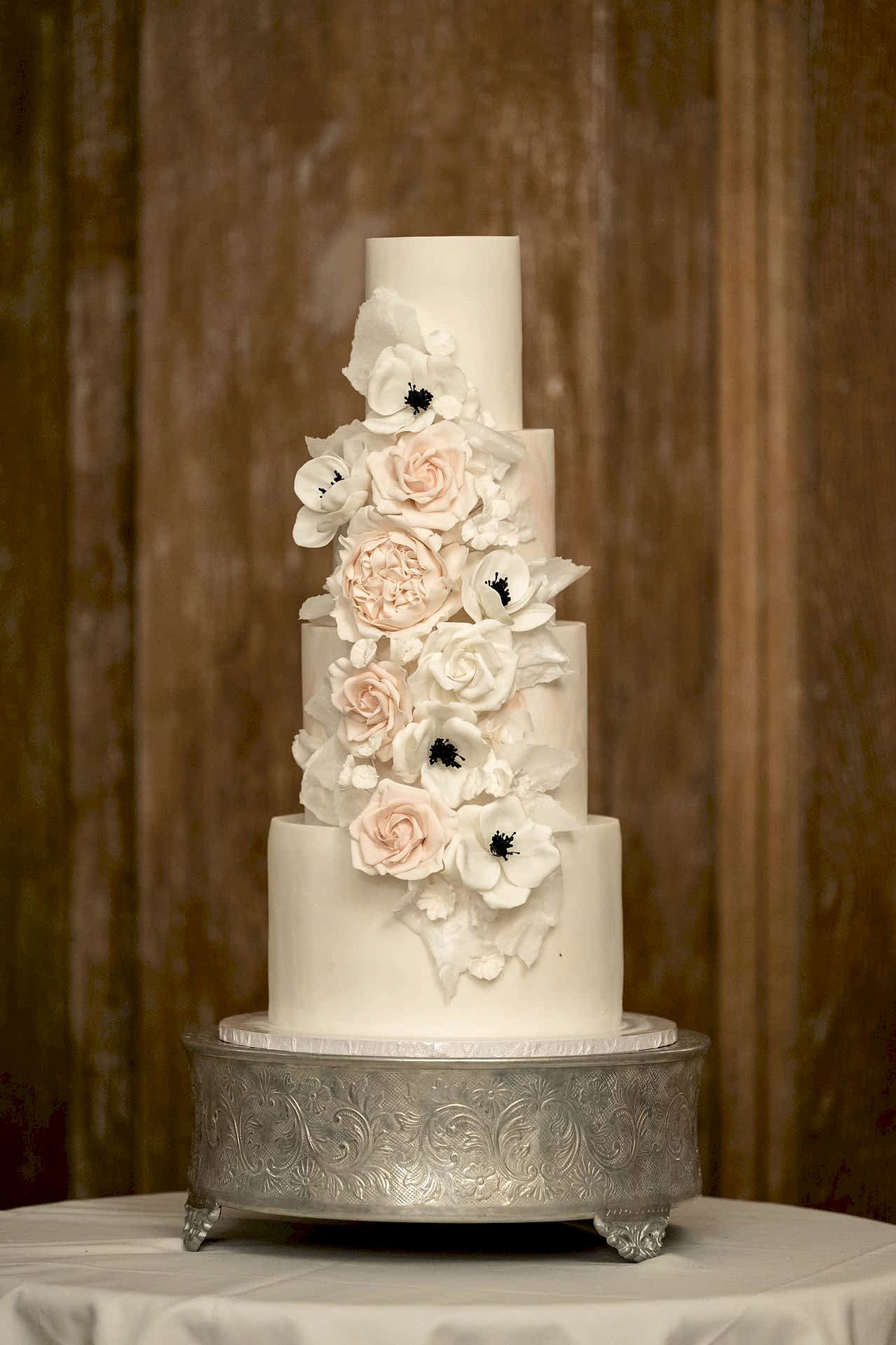 A four-tier wedding cake displayed in Knightley Court at Fawsley Hall