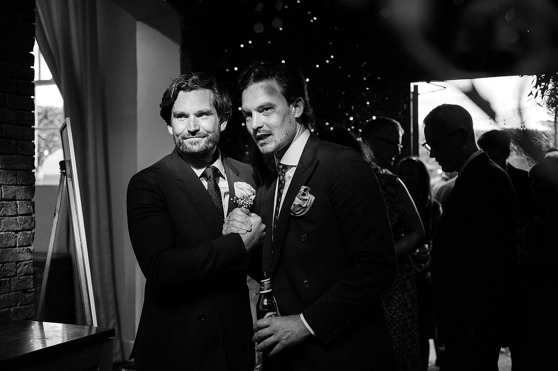 The groom greeting a friend during the receiving line in the foyer of Knightley Court at Fawsley Hall