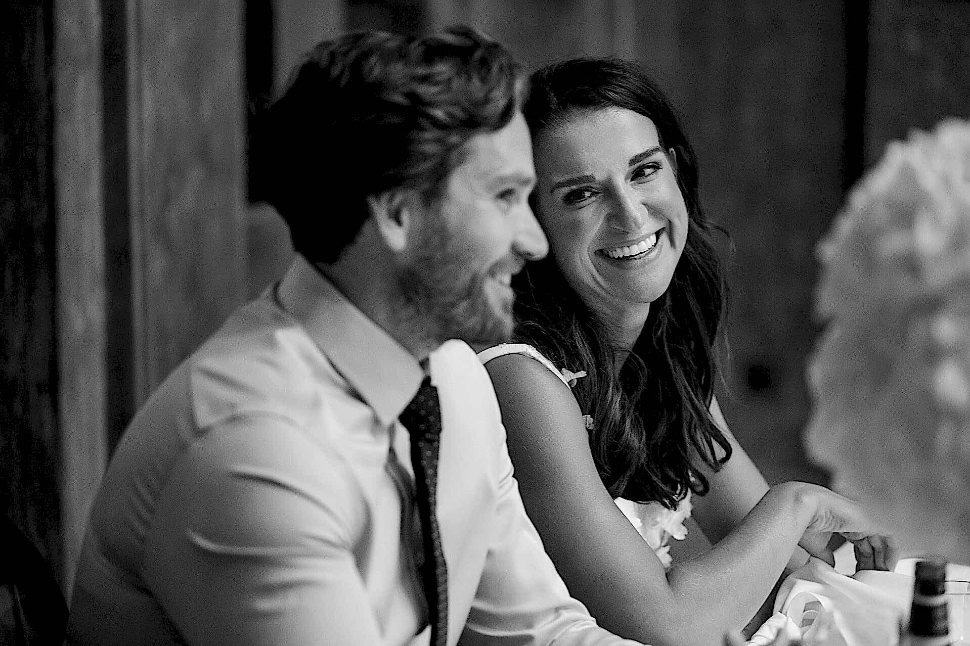 The bride with a big smile looking at the groom during the speeches