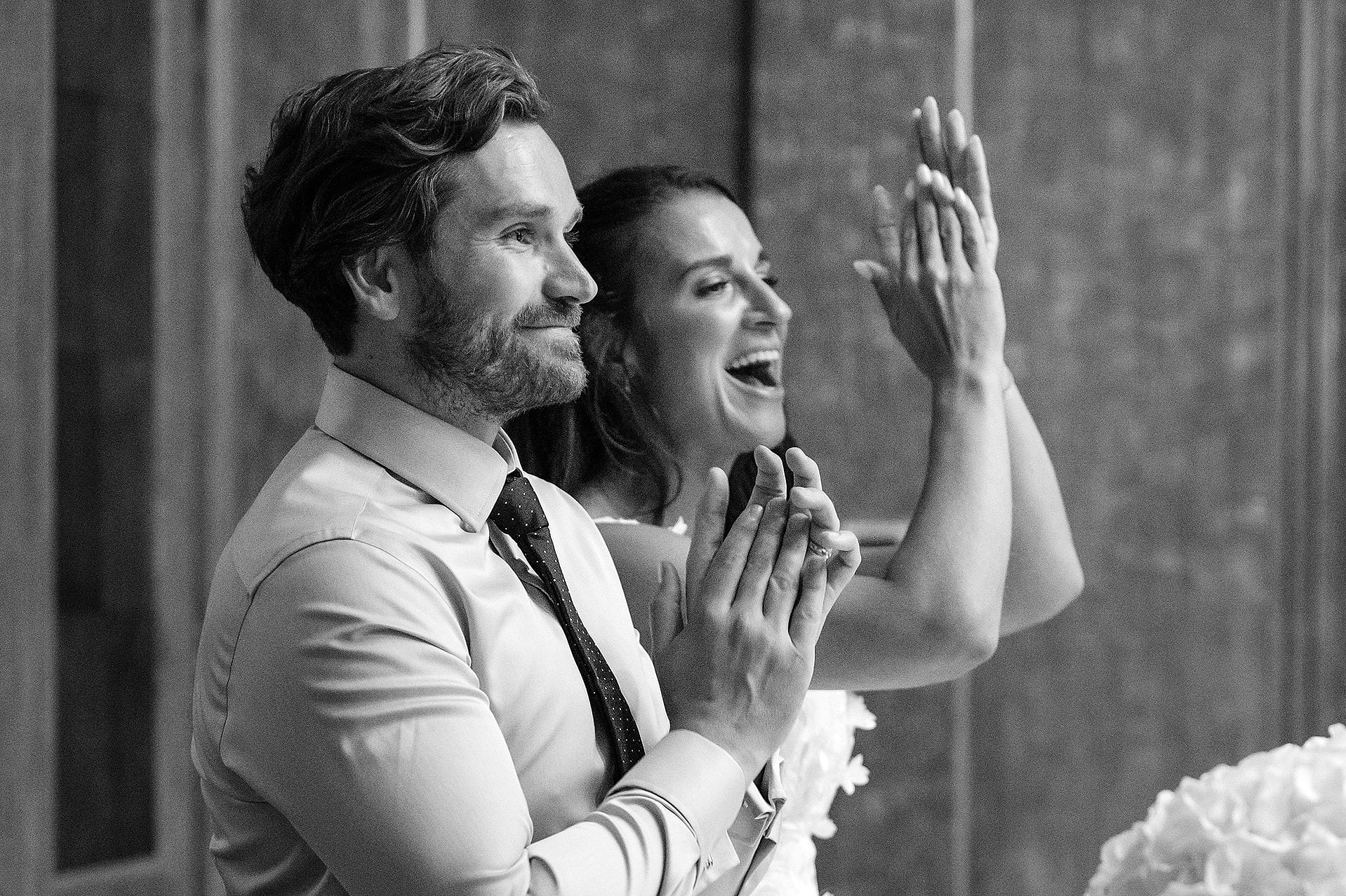 The bride and groom cheering for a bridesmaid who just finished a speech