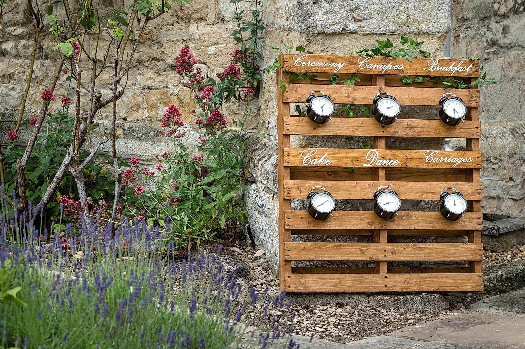 An order of the day sign made from a wooden pallet with old-fashioned alarm clocks set to the time for each event