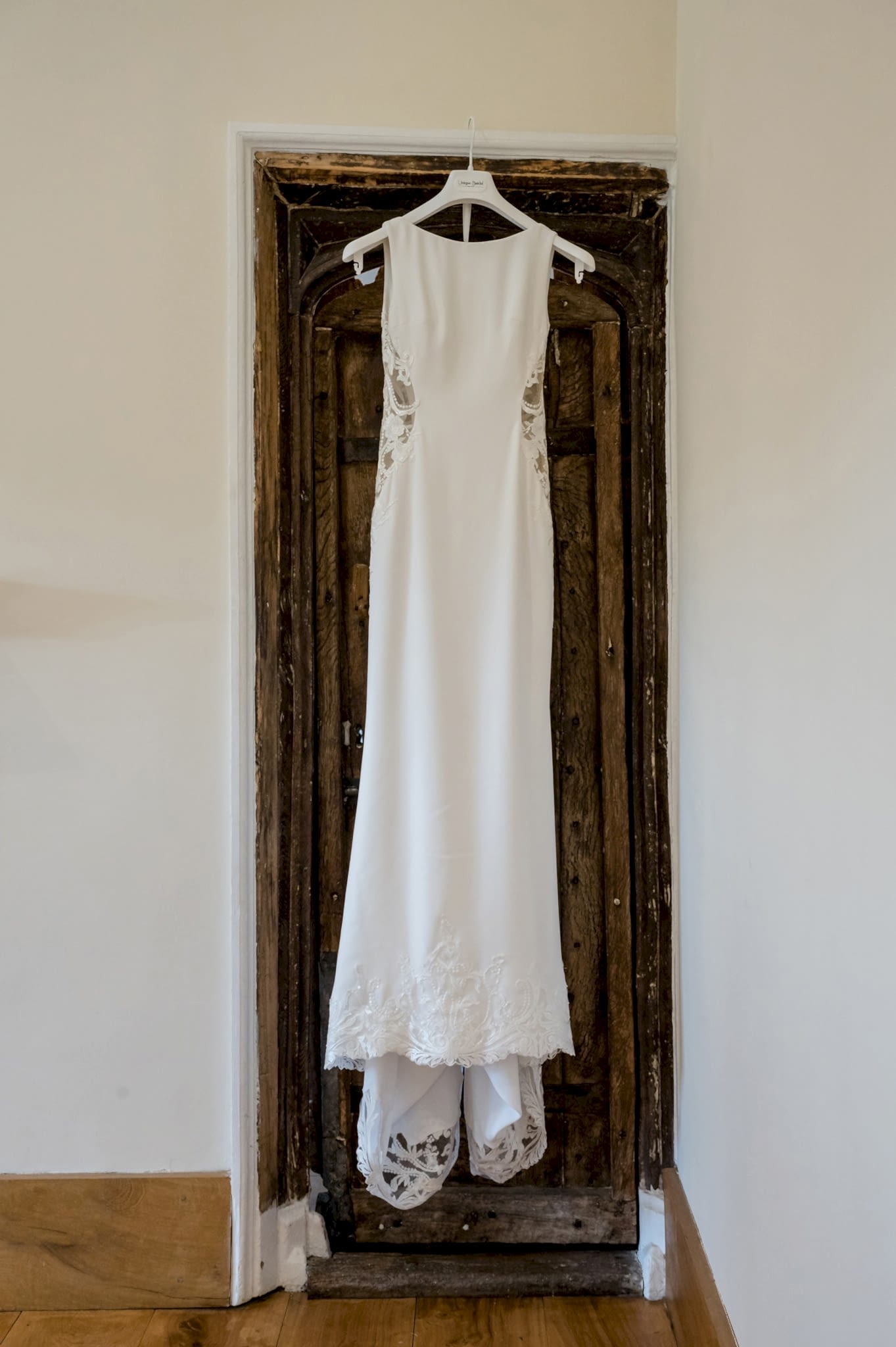 The bride's wedding dress hanging on an old door in the wedding suite at Notley Abbey
