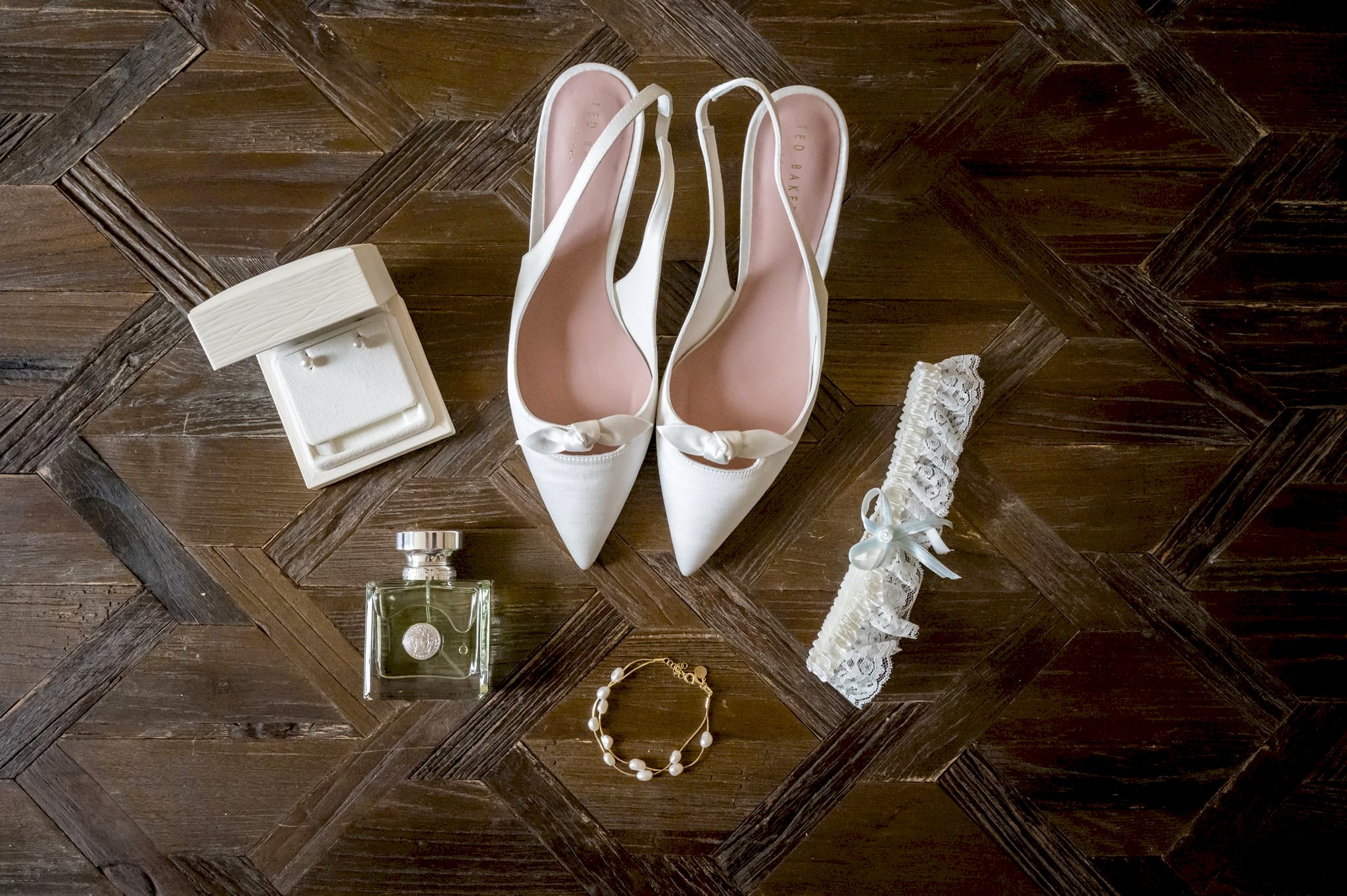 A flat-lay photo of the bride's shoes, perfume, and jewellery