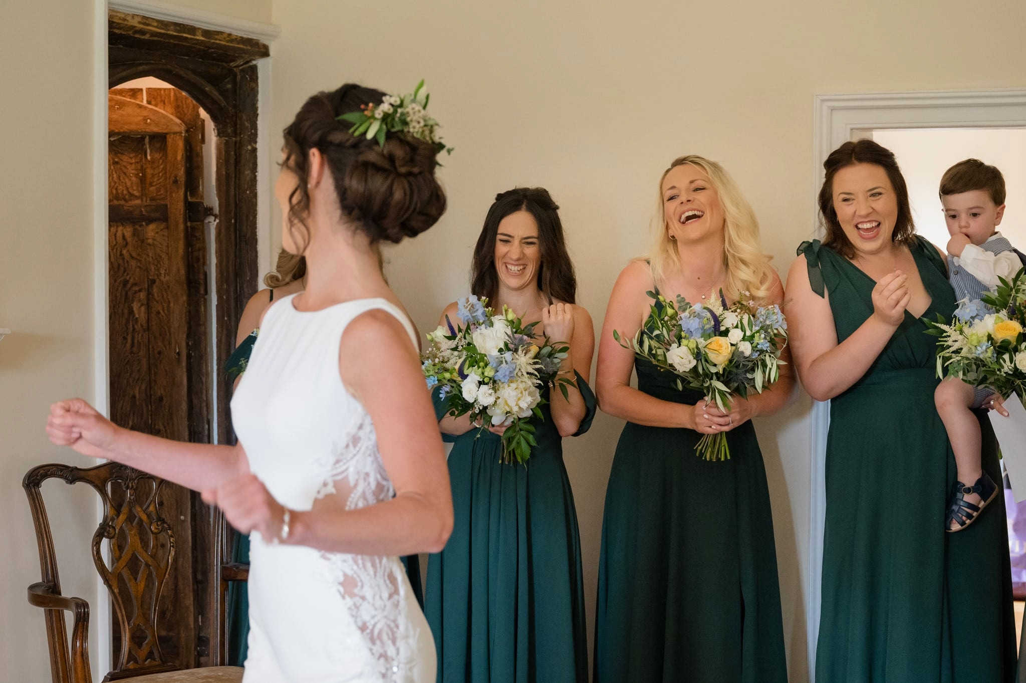 Bridesmaids reacting with big smiles as the bride does a twirl in her dress