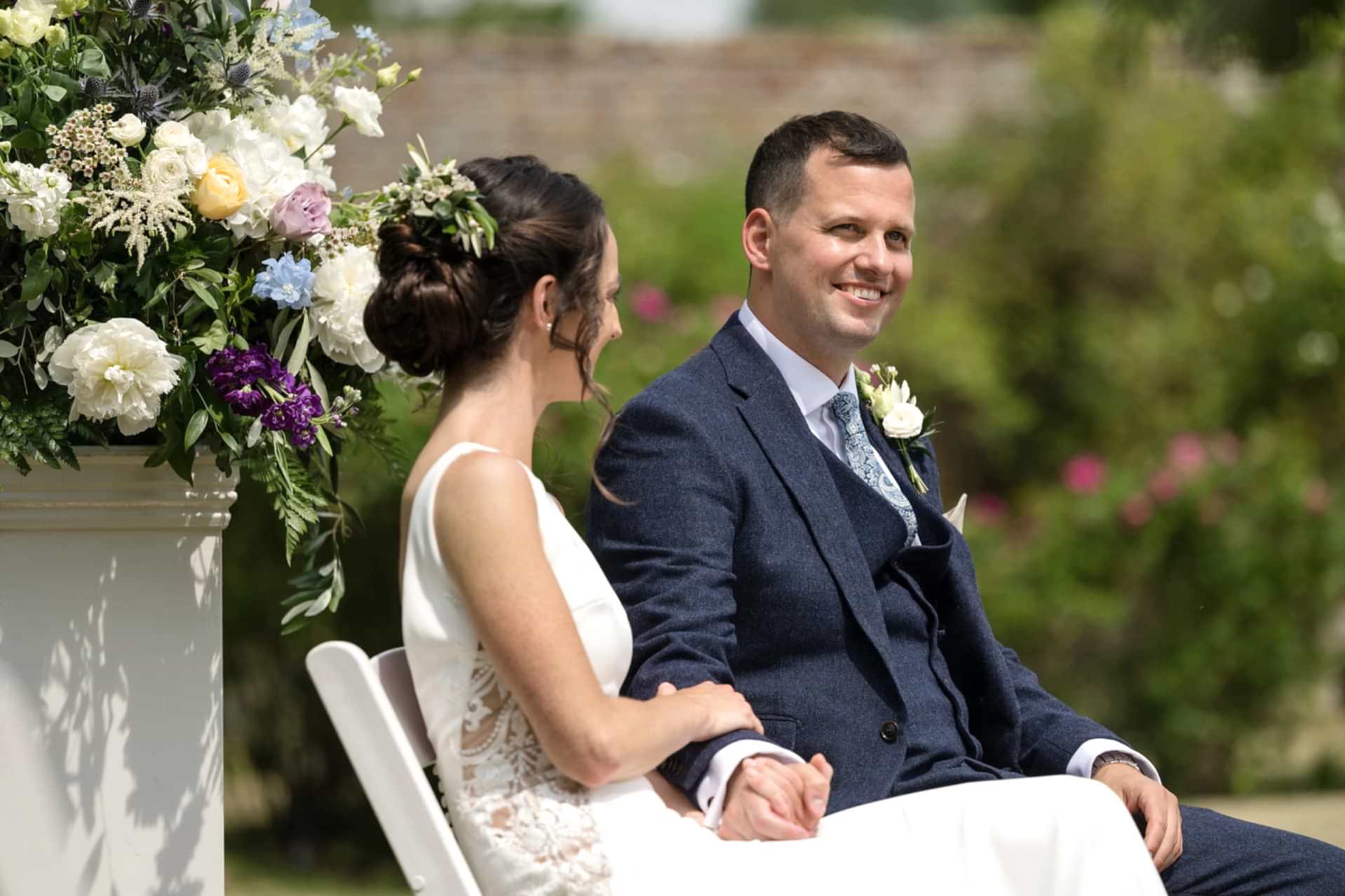 The groom smiling as the celebrant starts their wedding ceremony at Notley Abbey
