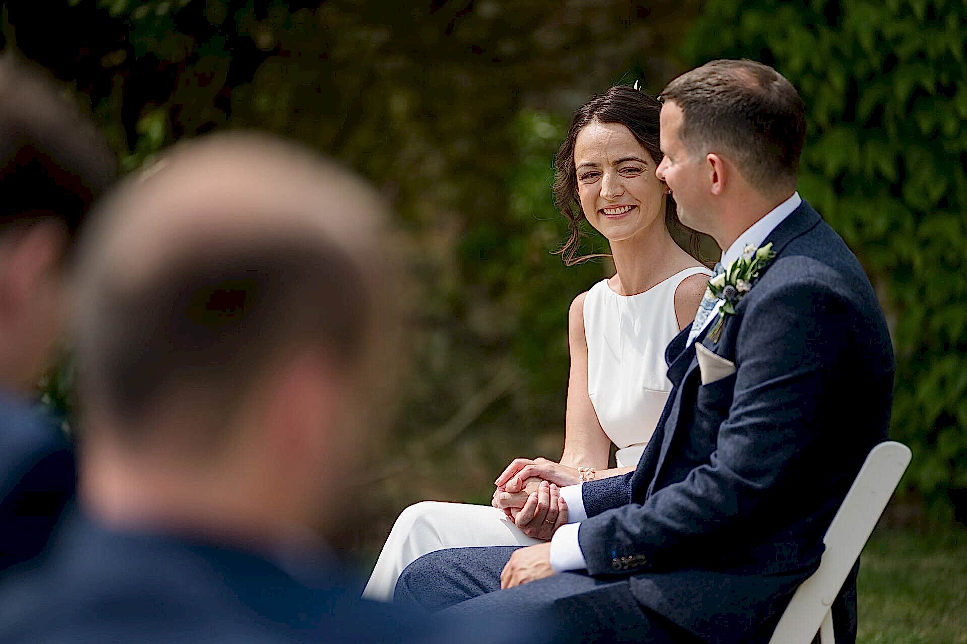 The groom looking happily at the groom during their outdoor celebrant wedding ceremony at Notley Abbey