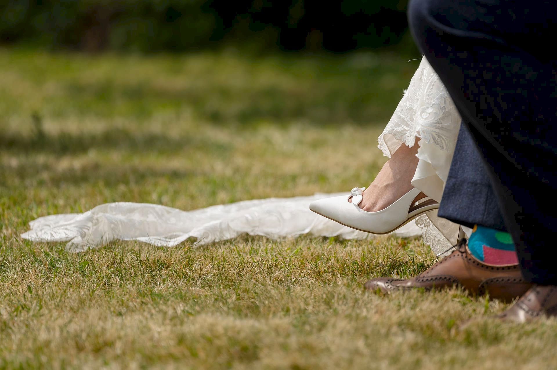 A close up photo of the bride and groom's feet showing the groom's brightly coloured socks and the bride's shoes