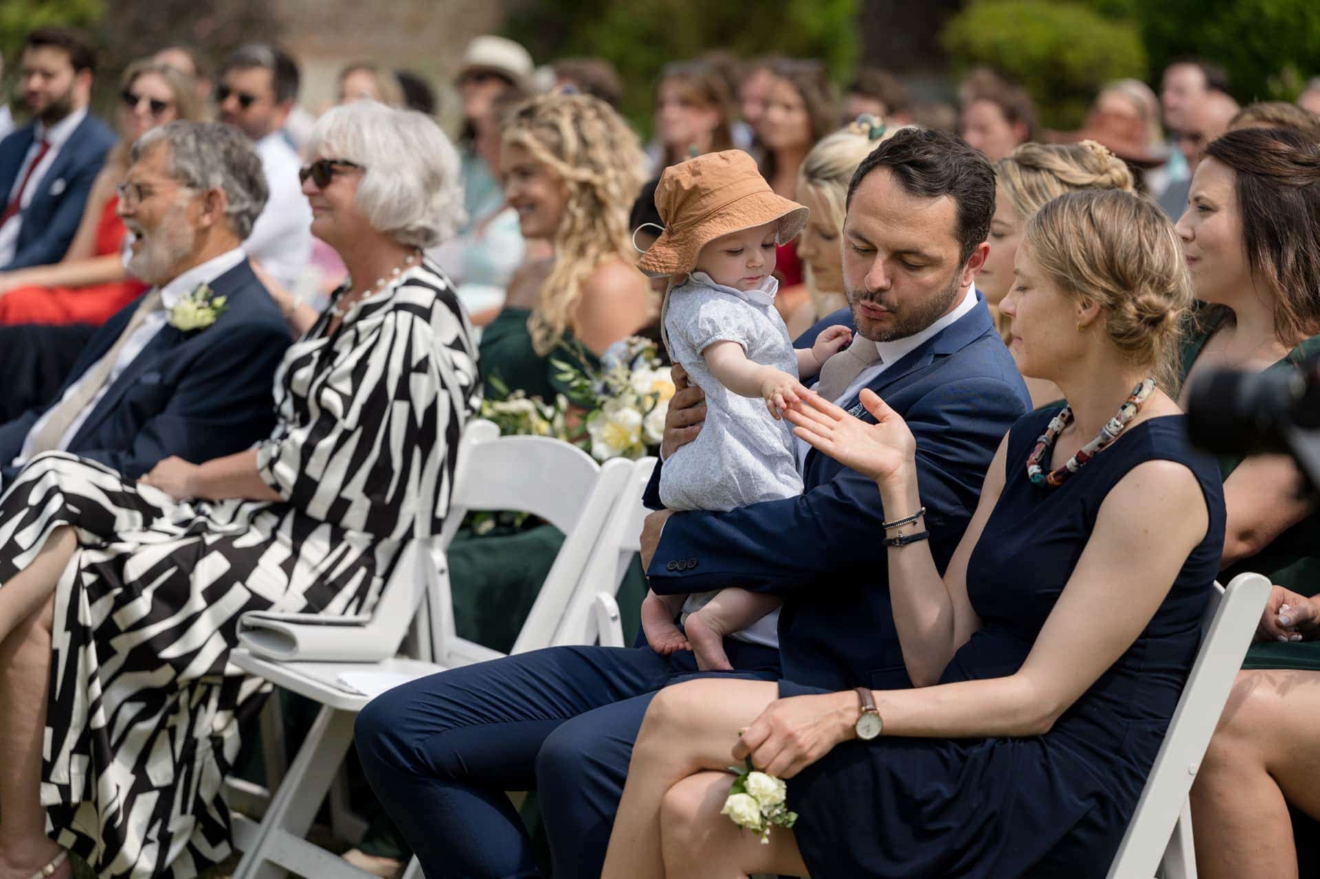 A small child reaching out to touch someone's hand during a wedding ceremony