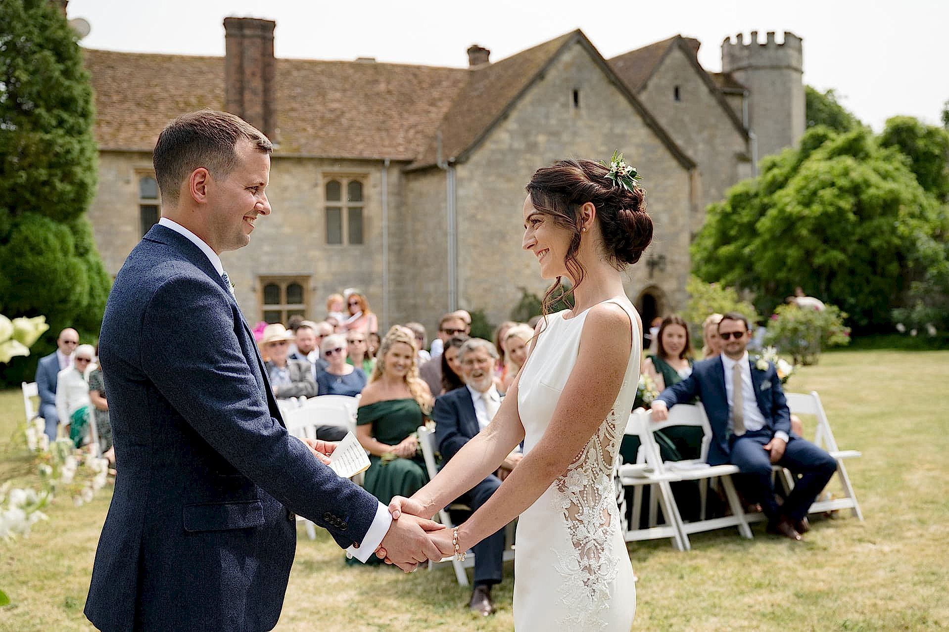 Bride and groom exchanging wedding vows in an outside ceremony with Notley Abbey in the background