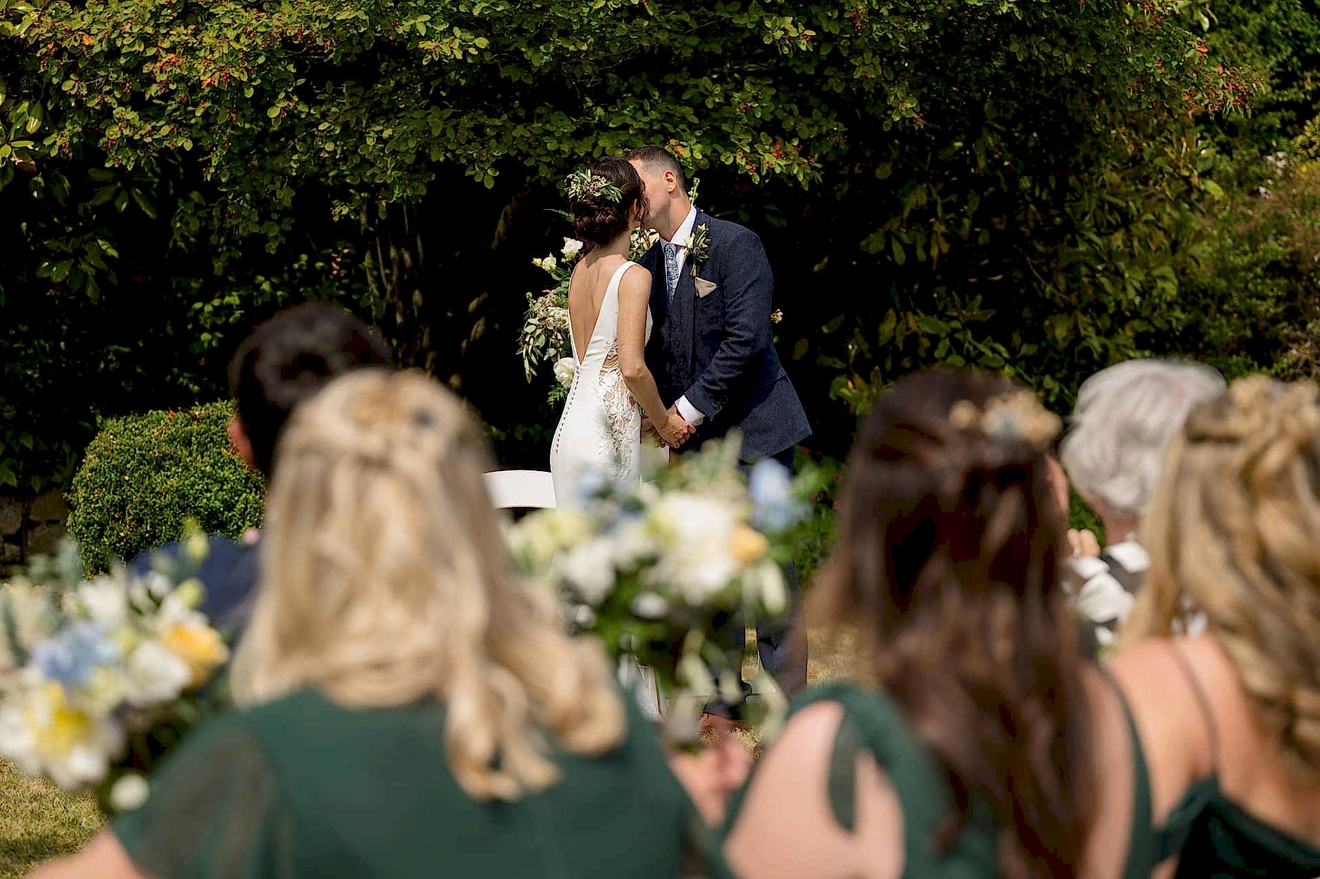 Bride and groom's first kiss with guests looking on