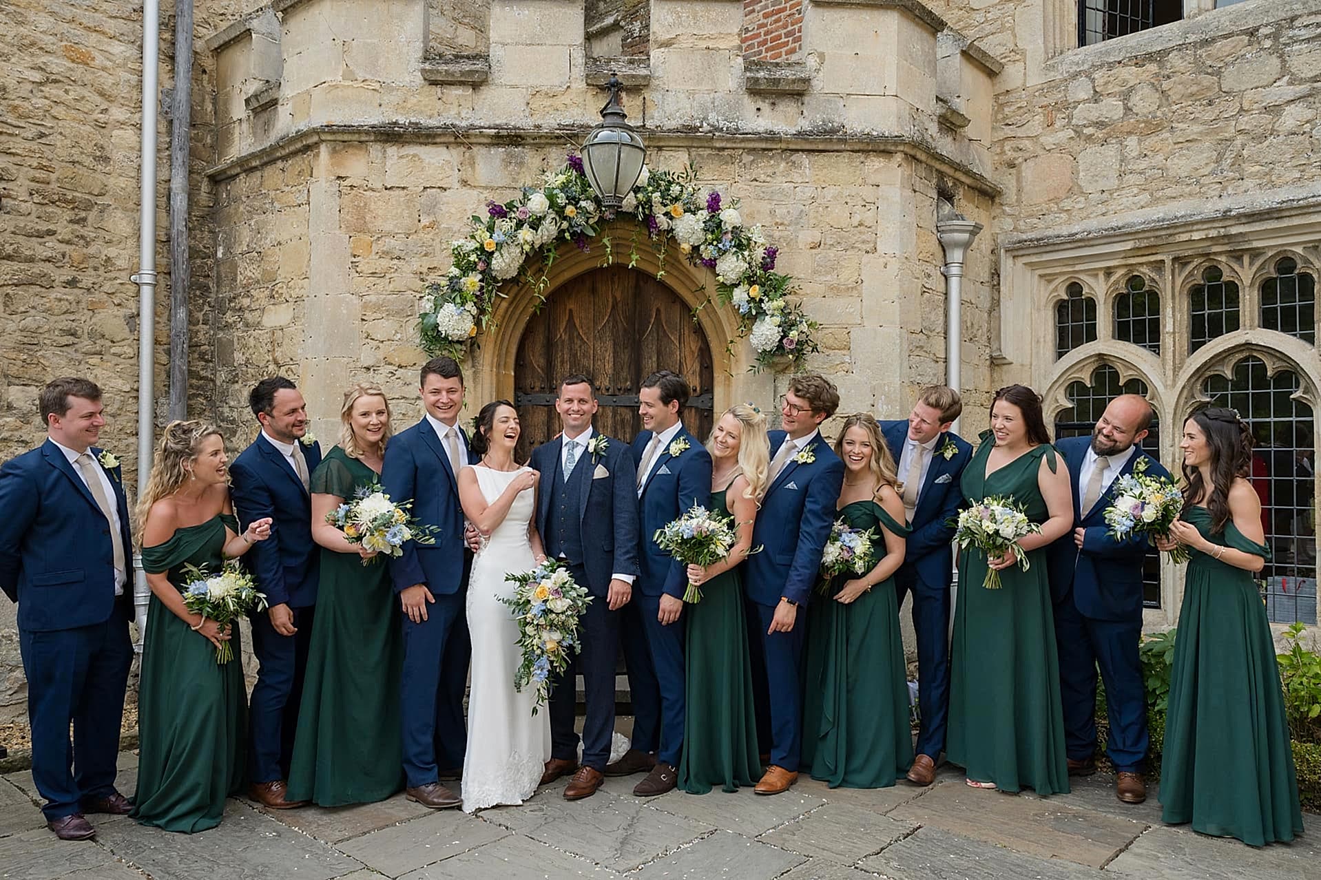 The bride and groom laughing with their bridesmaids and groomsmen during the group photos at Notley Abbey