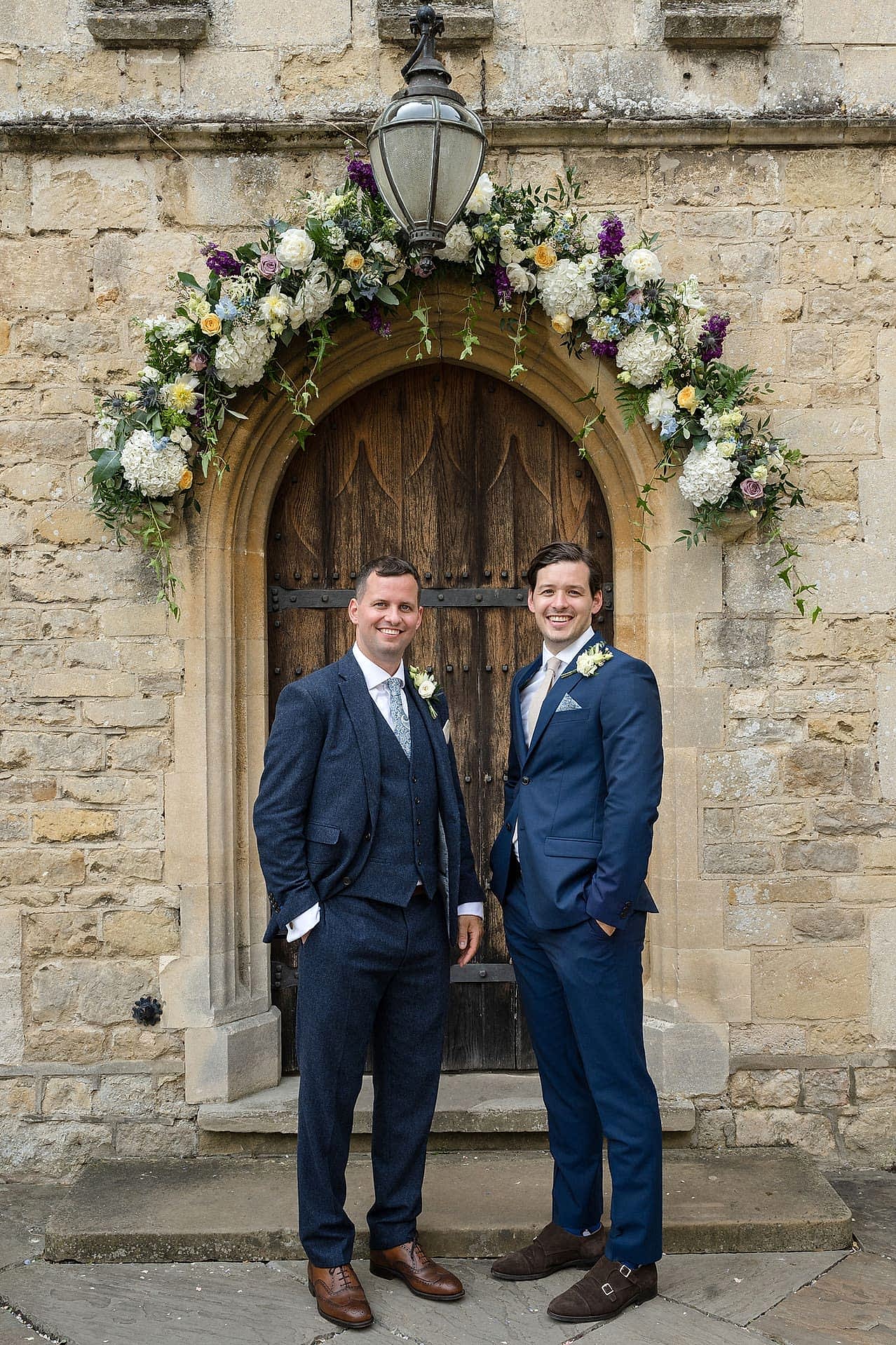 The groom and best man posing for a photo at the front door of Notley Abbey